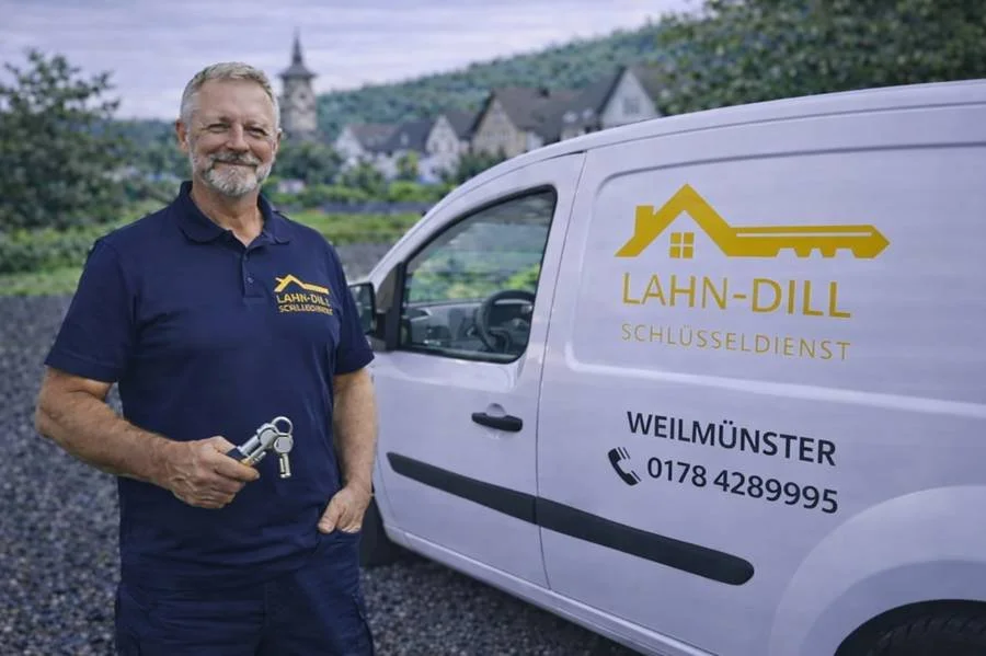 Schlüsseldienst Monteur in Weilmünster mit Servicefahrzeug und Schlüssel in der Hand