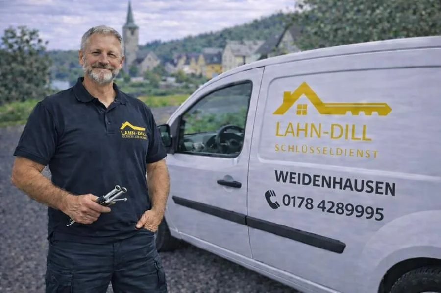 Erfahrener Schlüsseldienst-Monteur steht mit Werkzeug vor Einsatzfahrzeug in Weidenhausen