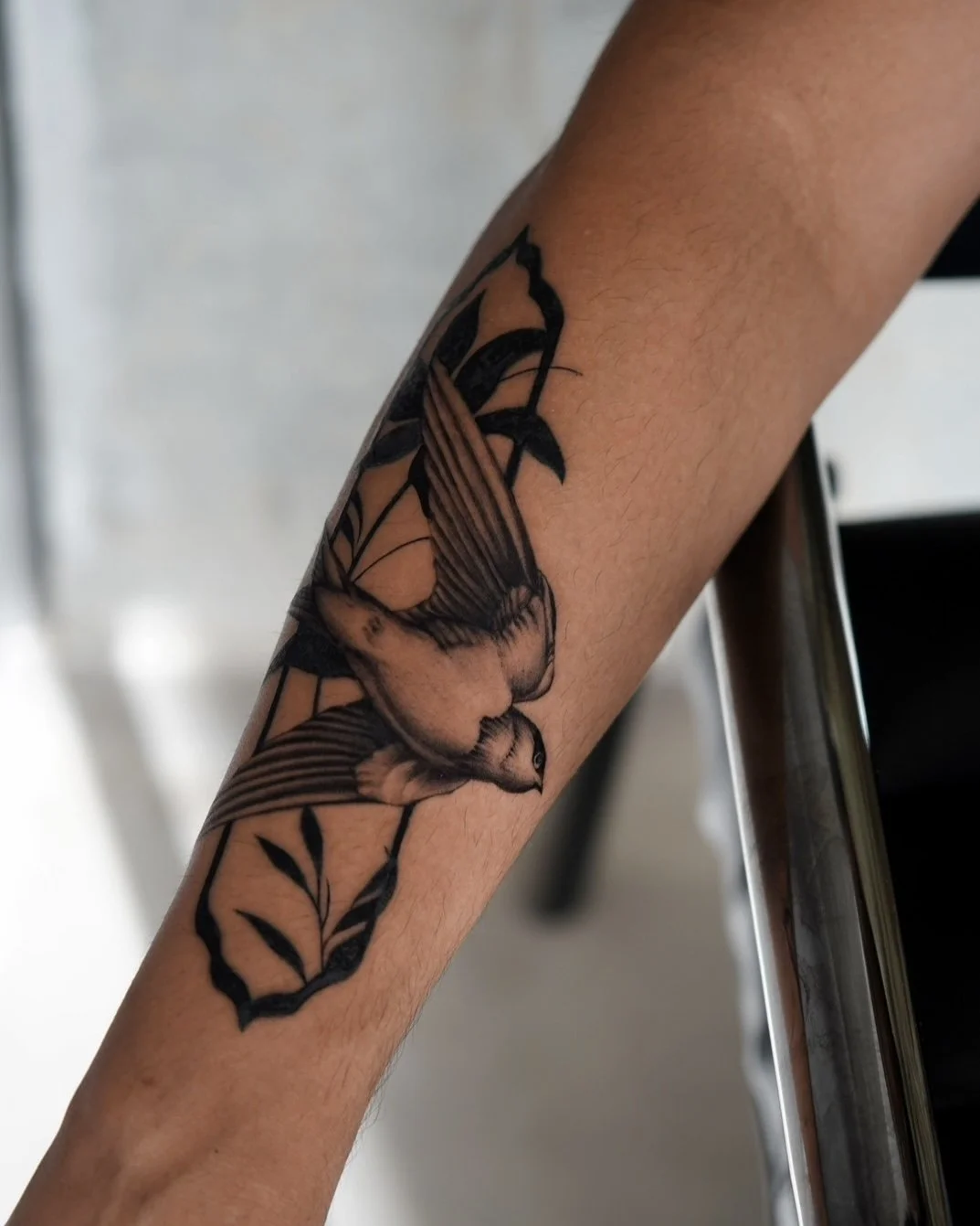 Tattoo of a hummingbird in black ink on a person's forearm.
