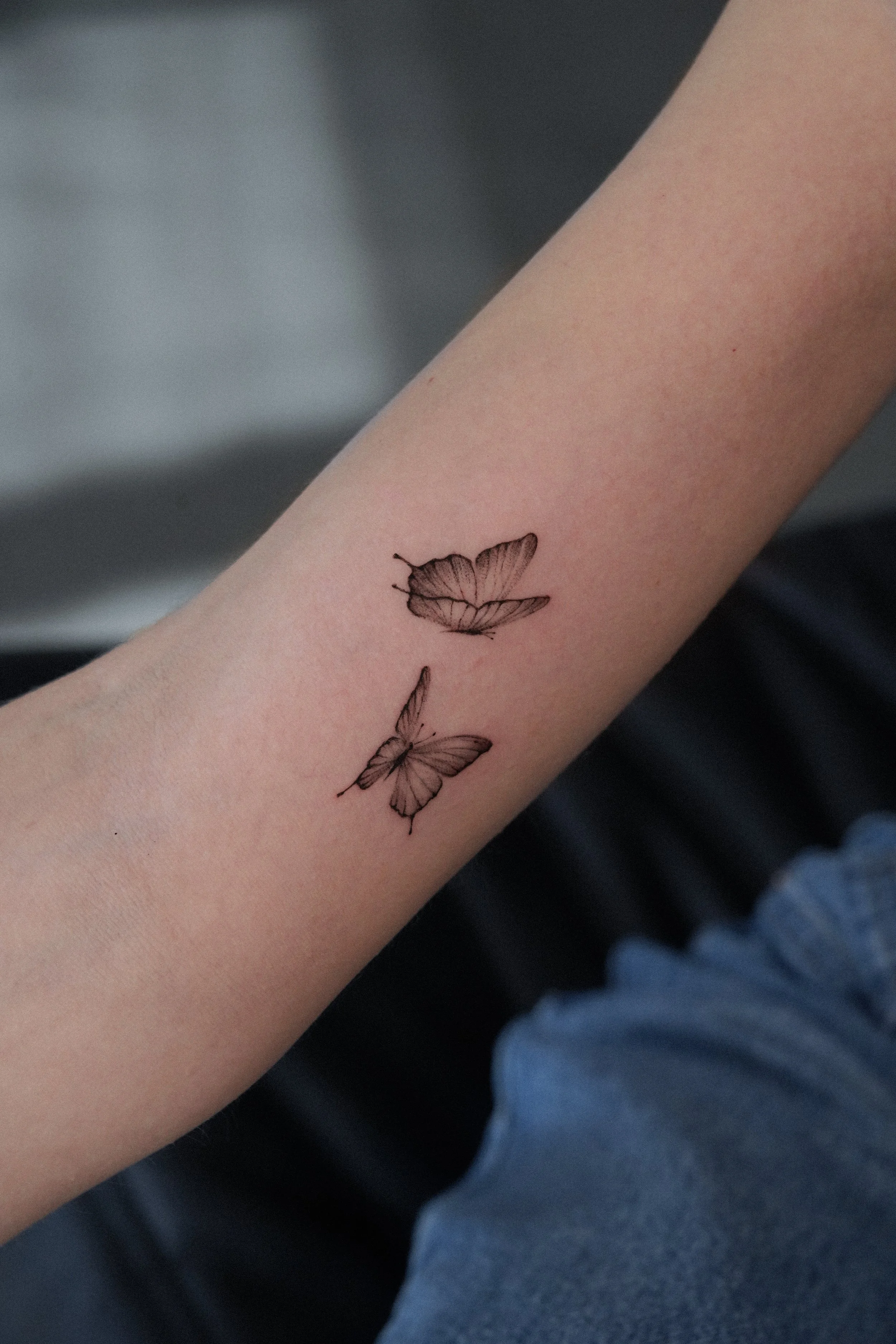 Tattoo of two butterflies on a person's inner forearm.