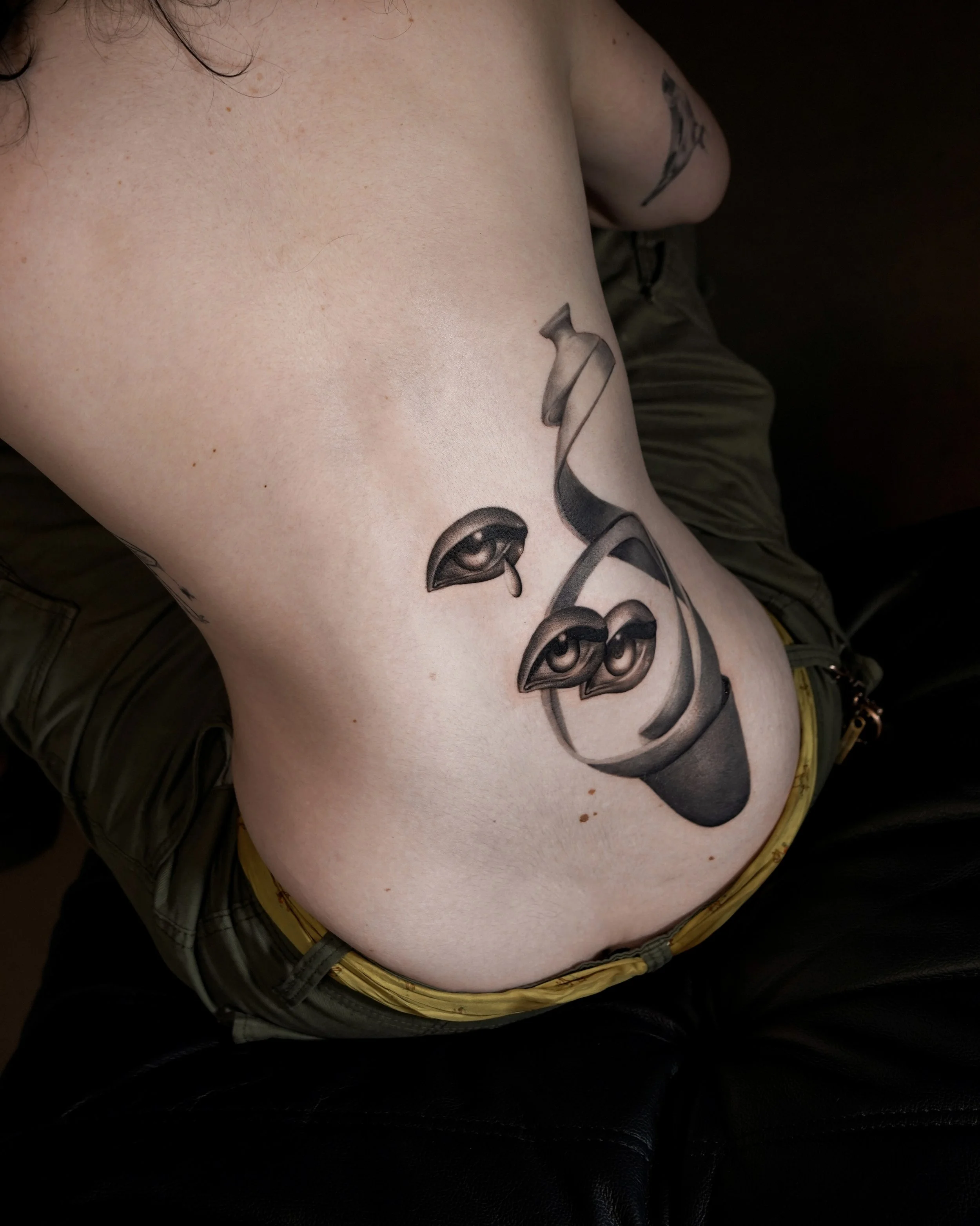 Tattoo of three eyes with teardrops on a person's side torso.