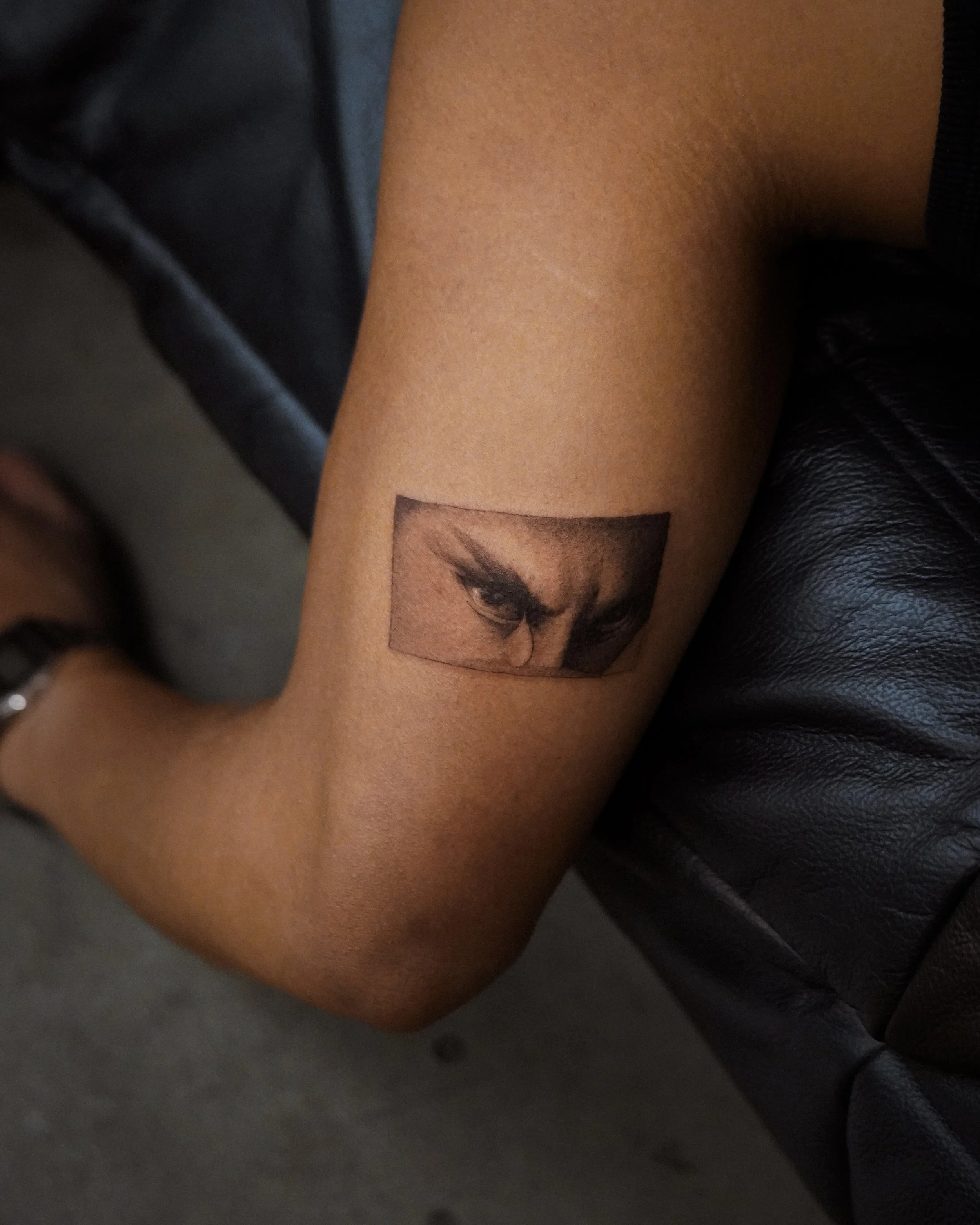 Tattoo of a person's eyes on inner forearm.