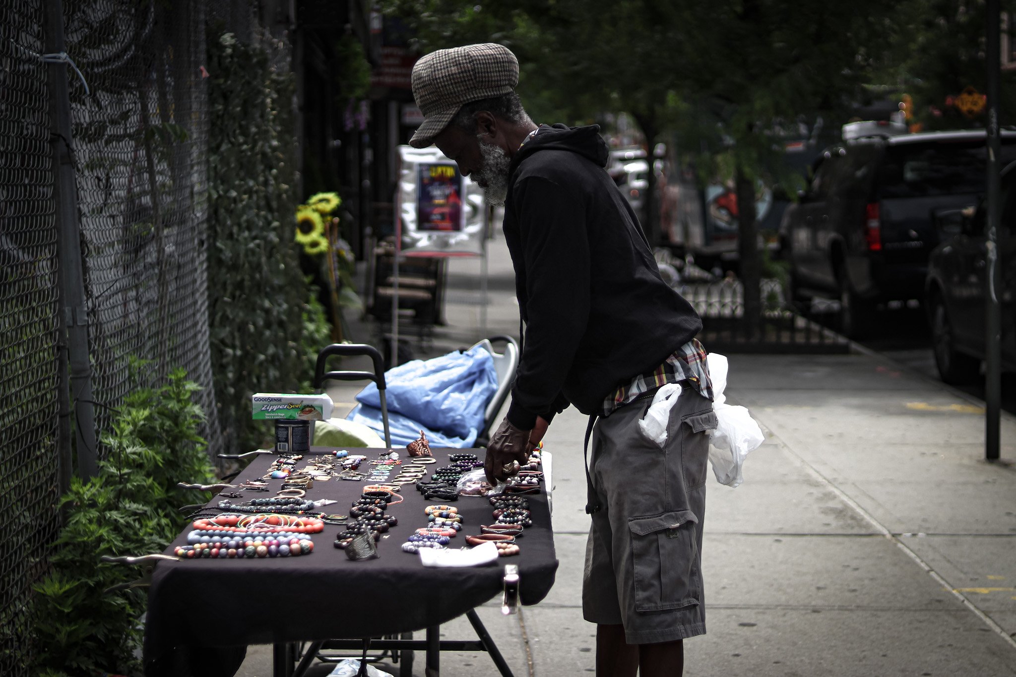 Street vendor arranging handmade jewelry on a table in an urban setting.