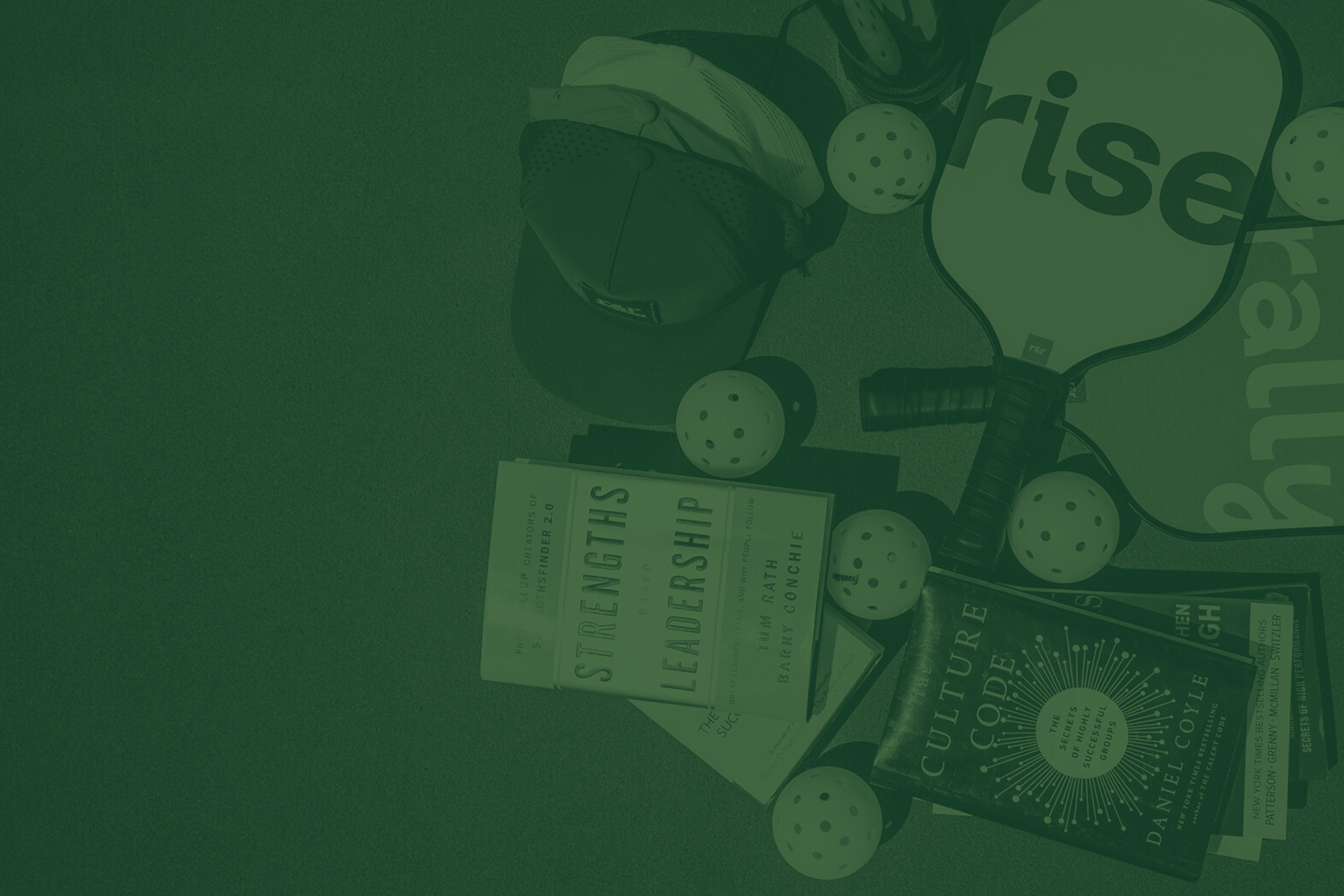 A collection of golf-related items including a cap, golf balls, a book titled 'The Culture Code' by Daniel Coyle, and another book titled 'Strengths Leadership' by Tom Rath, arranged on a surface.