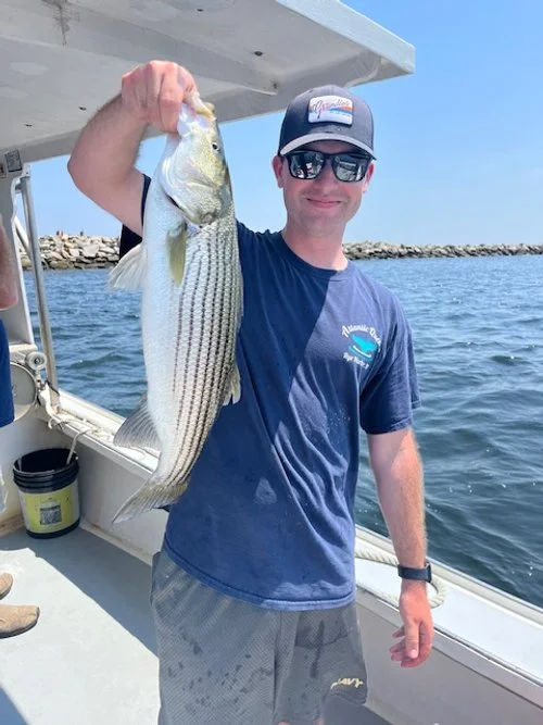 young man holding a fish on a boat on the ocean