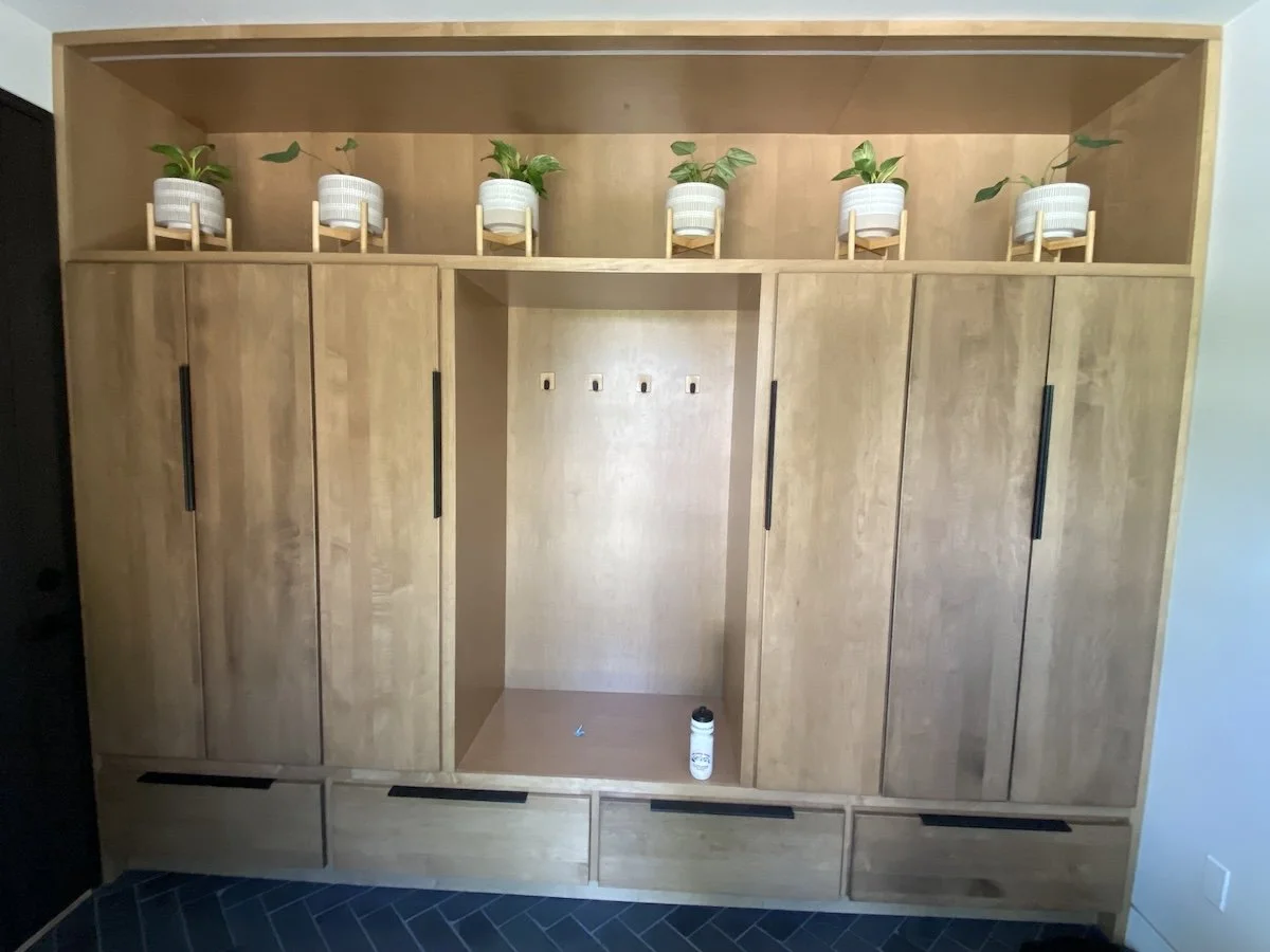 Wooden storage unit with cabinets and drawersinside a room with dark tile flooring.
