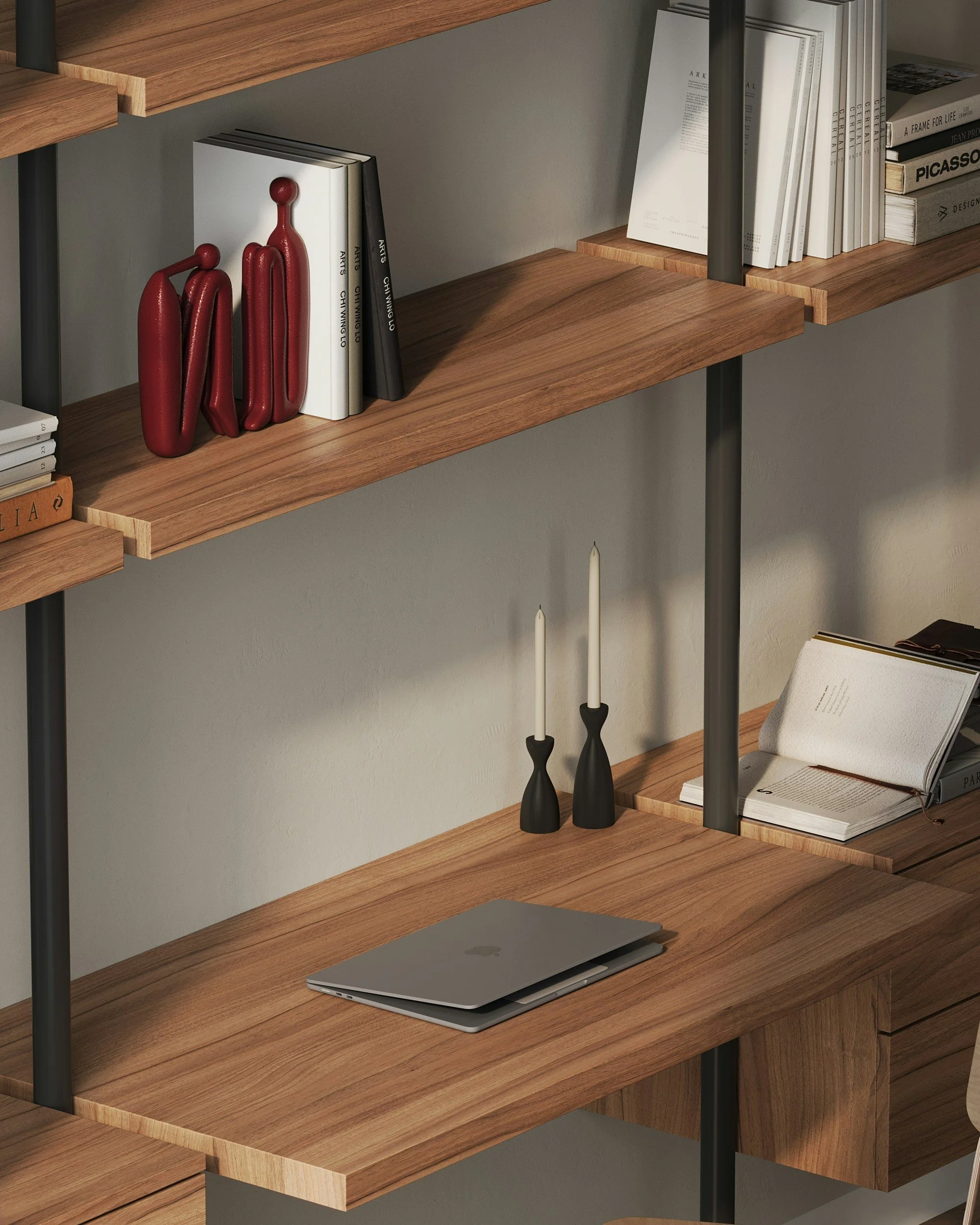 A wooden desk with a closed laptop, two black candlesticks with white candles, and a bookshelf with books and decorative objects. Hudson Valley home management services.