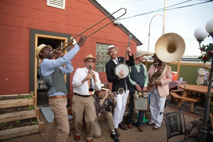 folk band playing in front of a red building outside