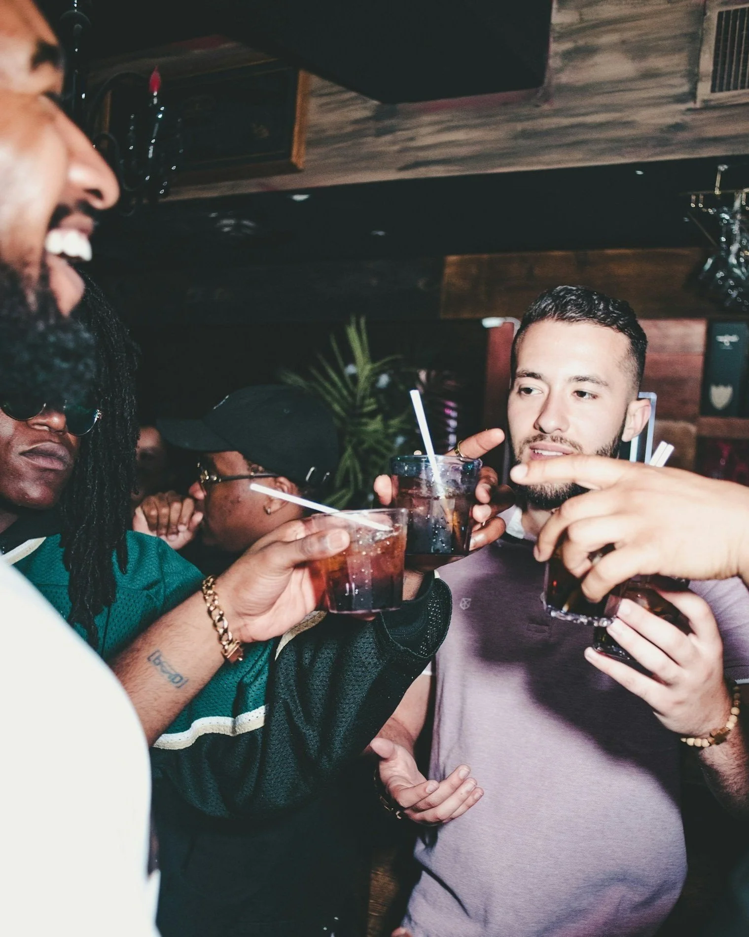 Group of people toasting with drinks in a dimly lit bar.