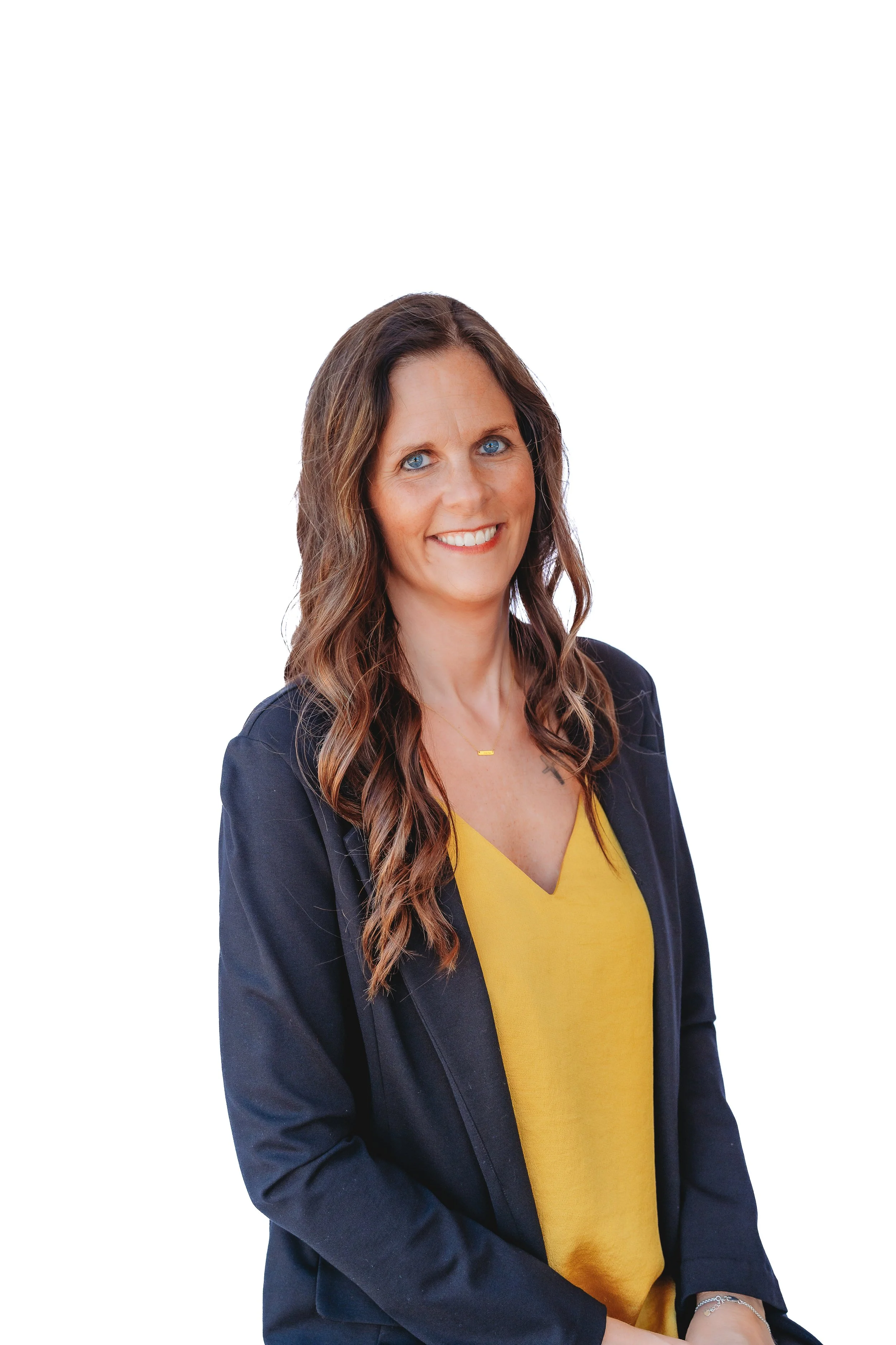 A woman with long brown wavy hair, blue eyes, wearing a navy blazer and yellow top, smiling against a plain white background.