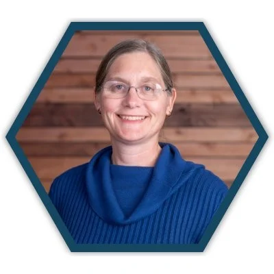 Portrait of Sarah Bushnell, member of the CityJoy board of directors, smiling in front of a wooden background.