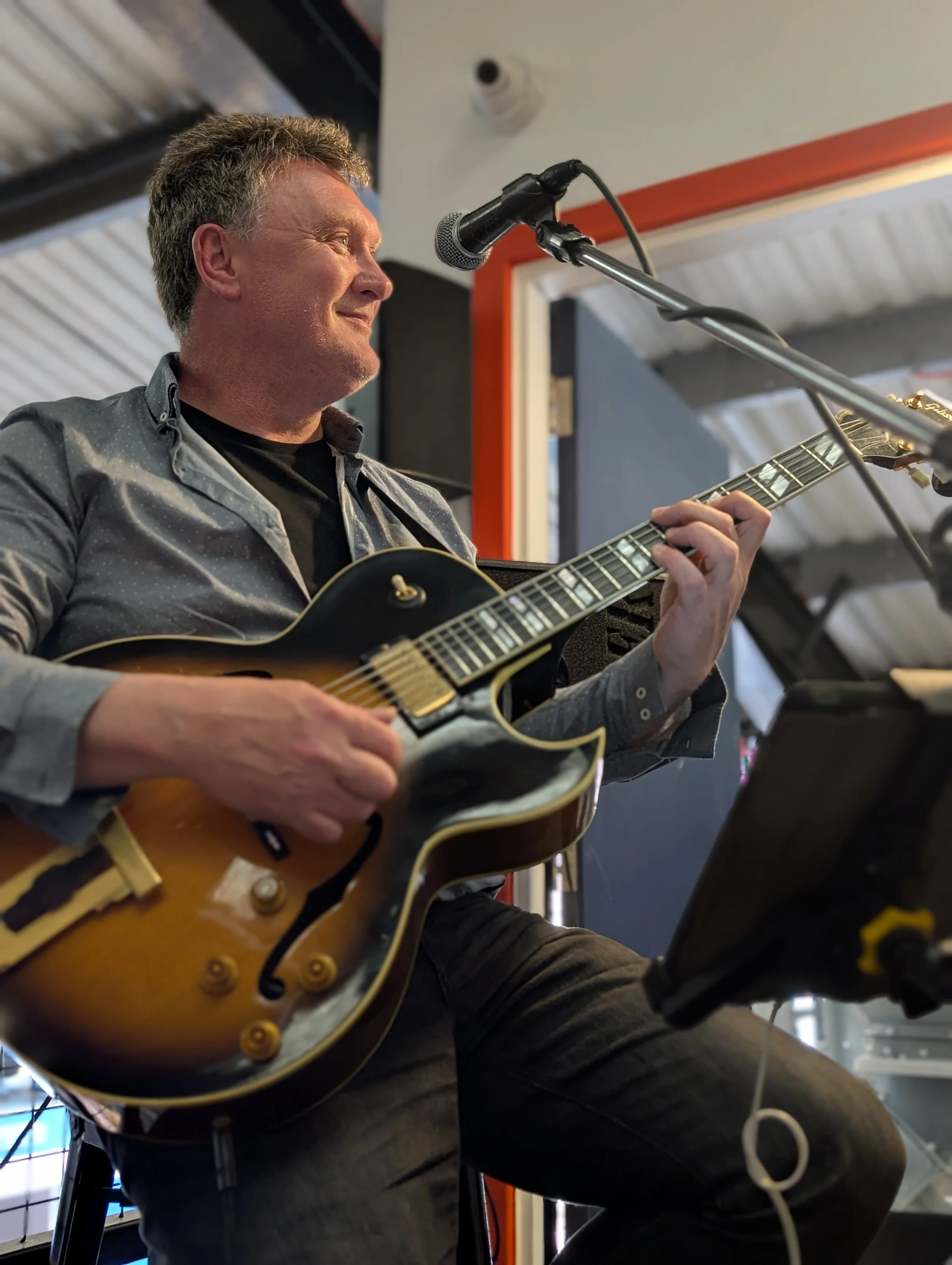 A man playing an electric guitar and singing into a microphone during a live music performance.