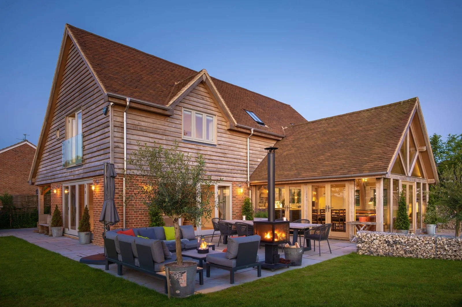 Completed Hill Top House with an outdoor seating terrace beside the glazed oak-frame living space, Dummer, Hampshire.