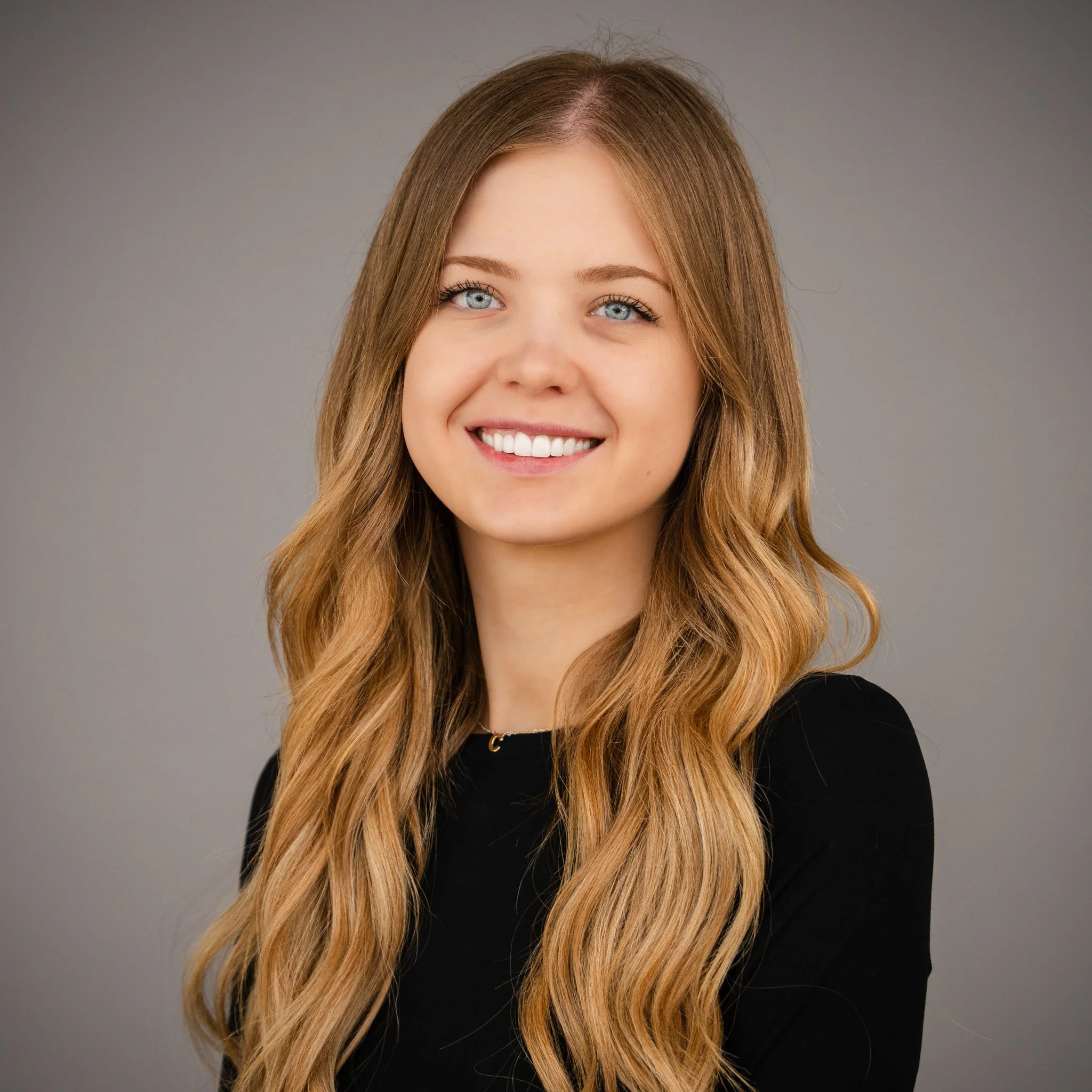 Smiling woman with long red hair wearing a black blazer.