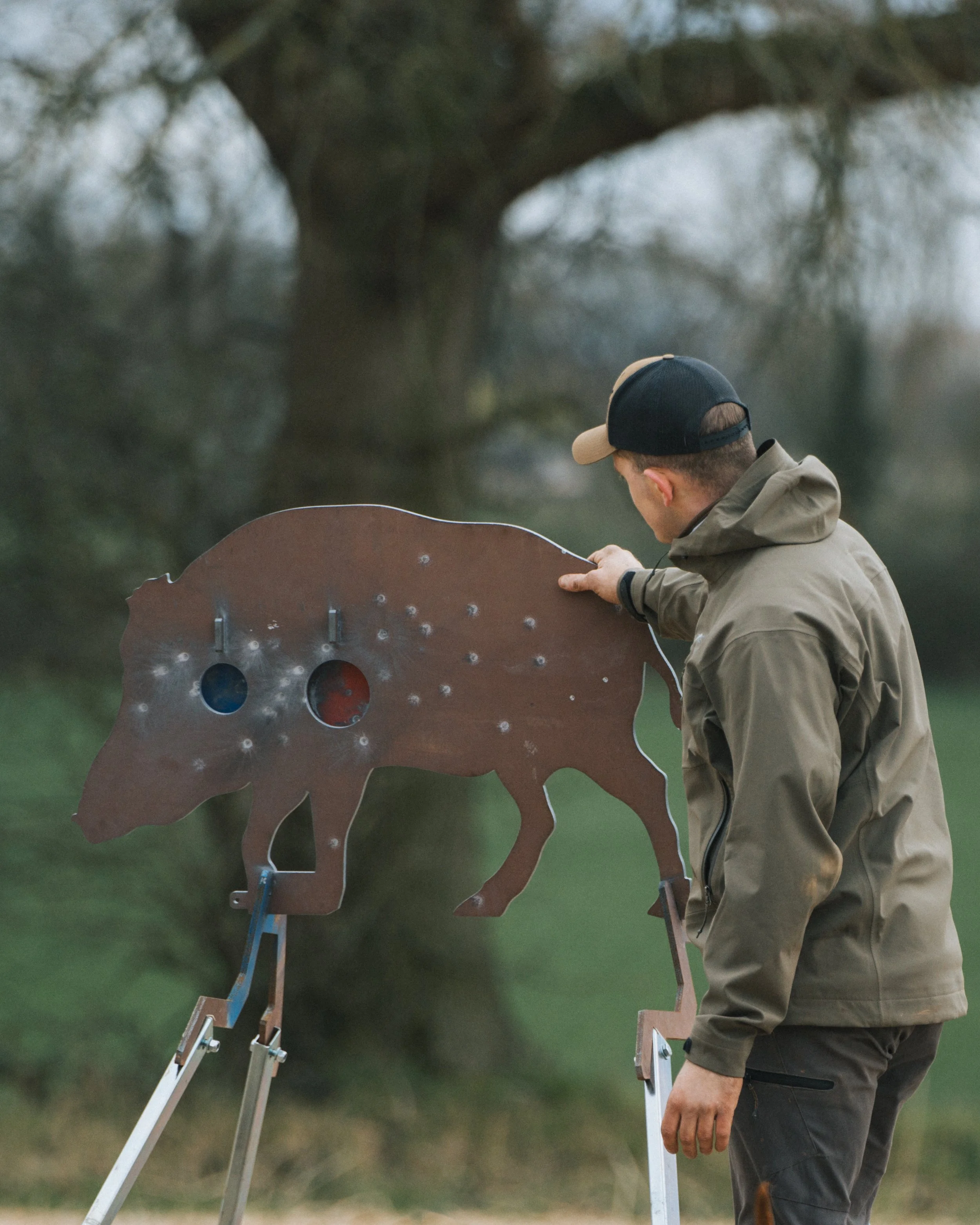 Person examining metal boar target outdoors