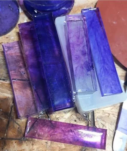 A collection of test resin pieces in various shades of purple and pink.