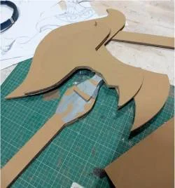 Unfinished cardboard axe prop on a green cutting mat