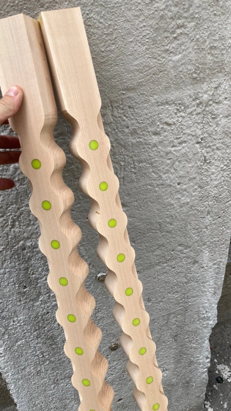 Two wooden leveling guides with yellow circular bubbles, held against a textured wall.