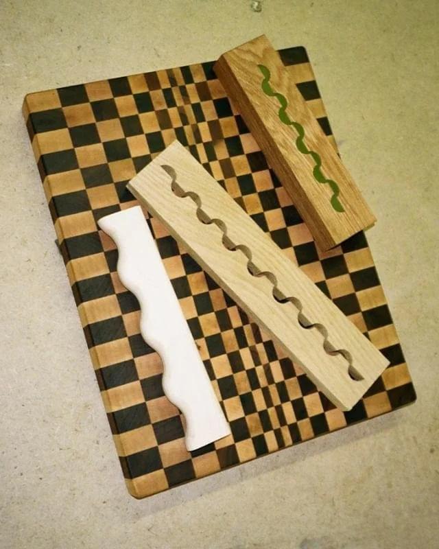 Three wooden chess boards with varying colors and patterns, placed on a larger checkered chessboard surface.