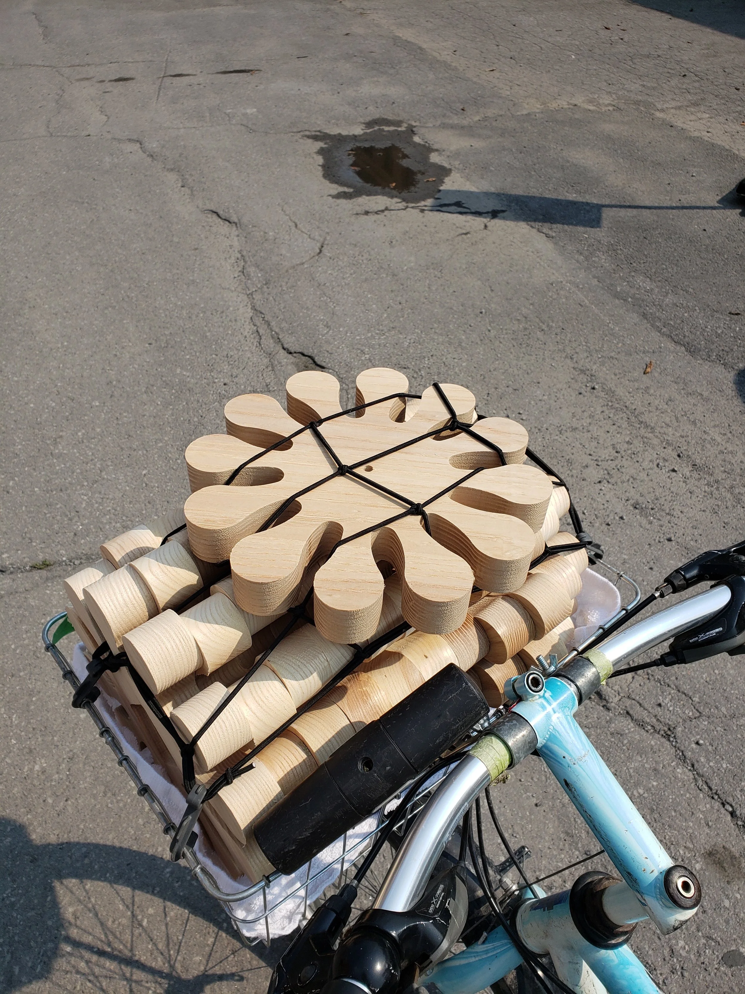 A bicycle with a basket carrying wooden toys shaped like flowers and heart-shaped objects.