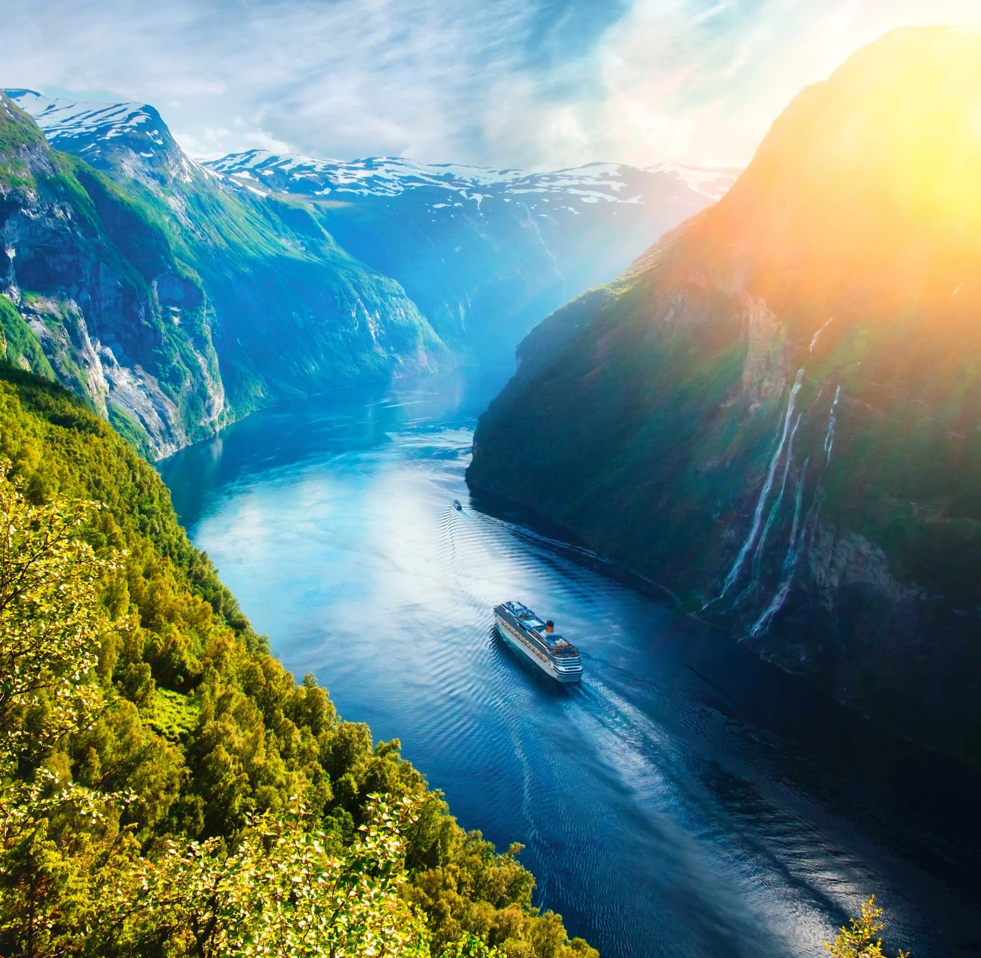 A cruise ship sails through a channel bookended by mountains in Norway