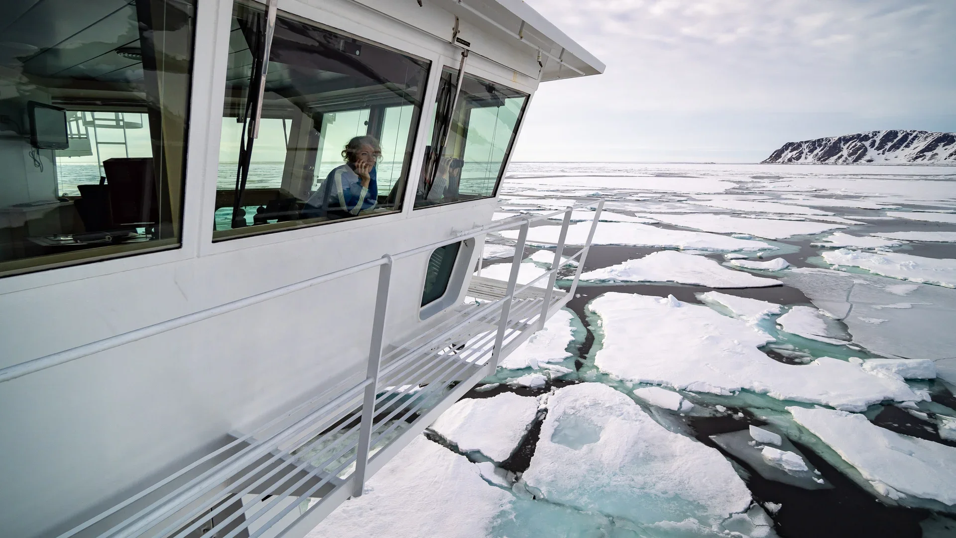 Woman gazes from the bridge of the HX Fram cruise ship among ice sheets in Antarctica