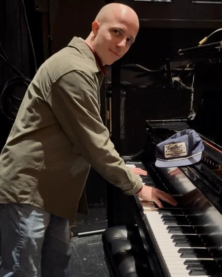 Person playing a piano with a hat on top.