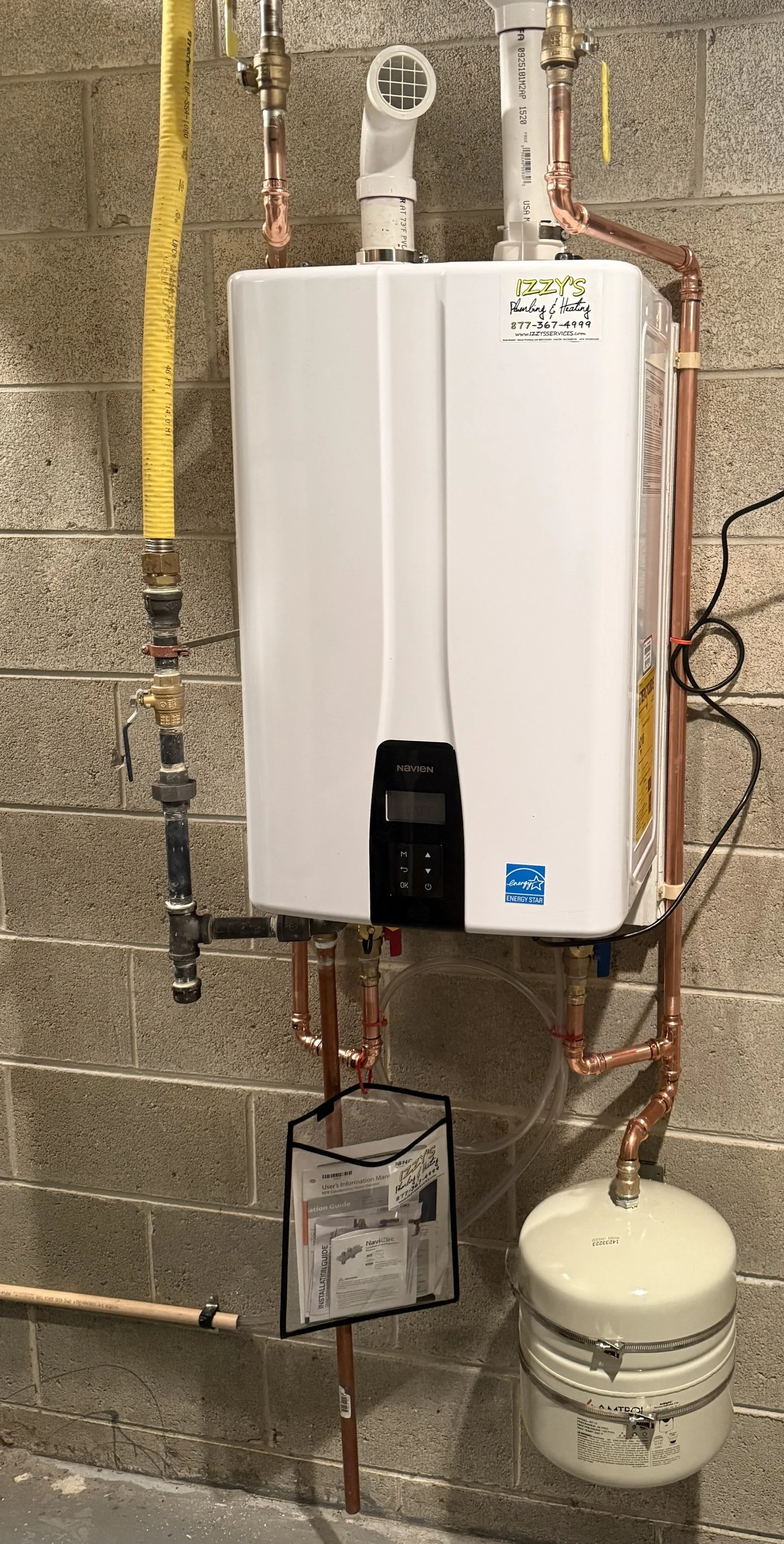 Professional Navien tankless water heater installation by certified plumbing technician in residential utility room, high-efficiency condensing unit mounted on wall.