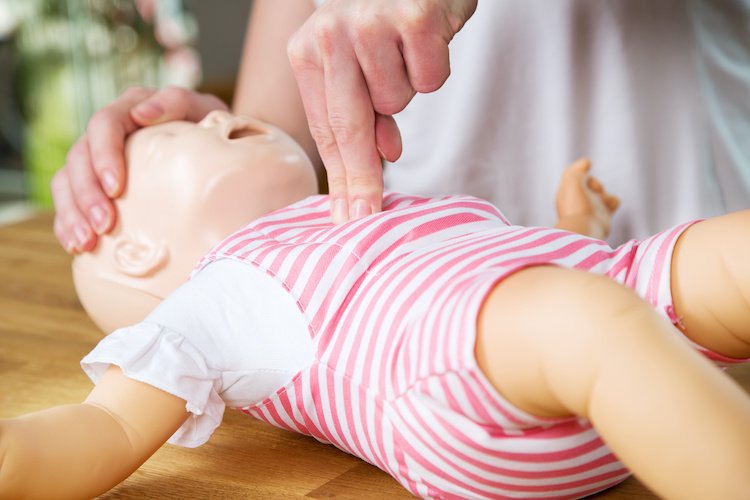 Person performing CPR on a baby mannequin during a training session.