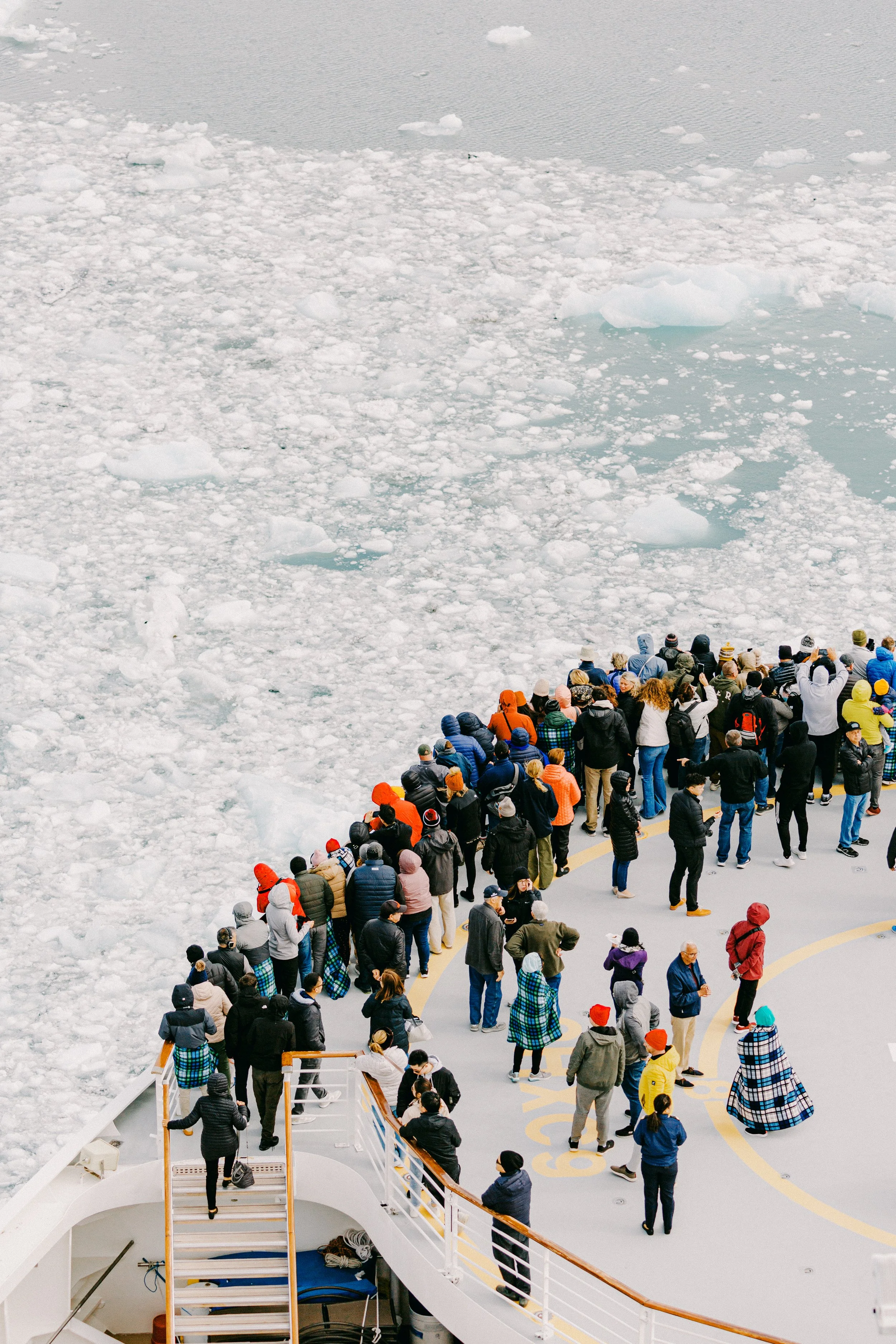 Crowd of people on a deck looking at floating ice and icy waters.