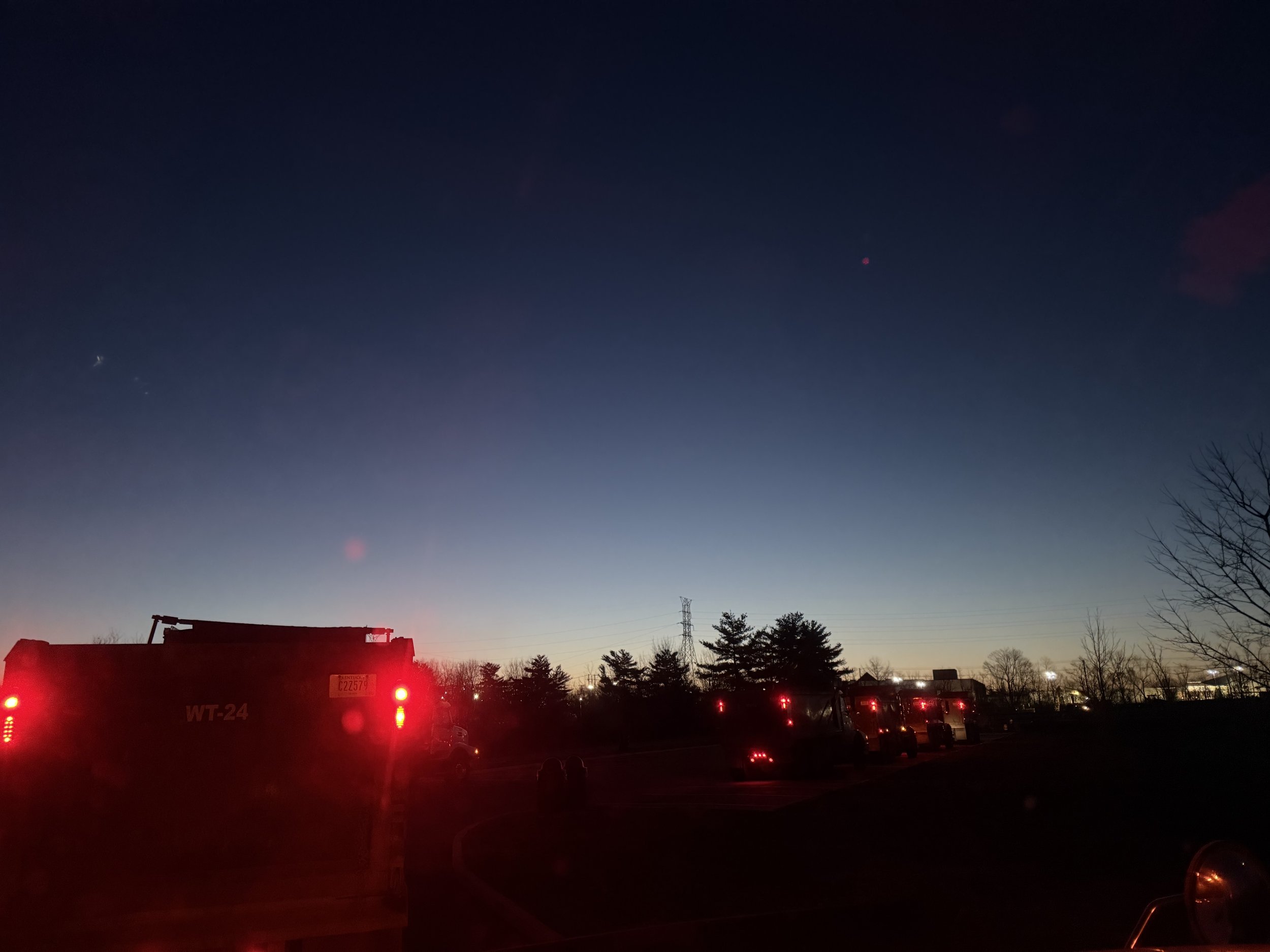 dump truck lights with trucks lined up before sunrise