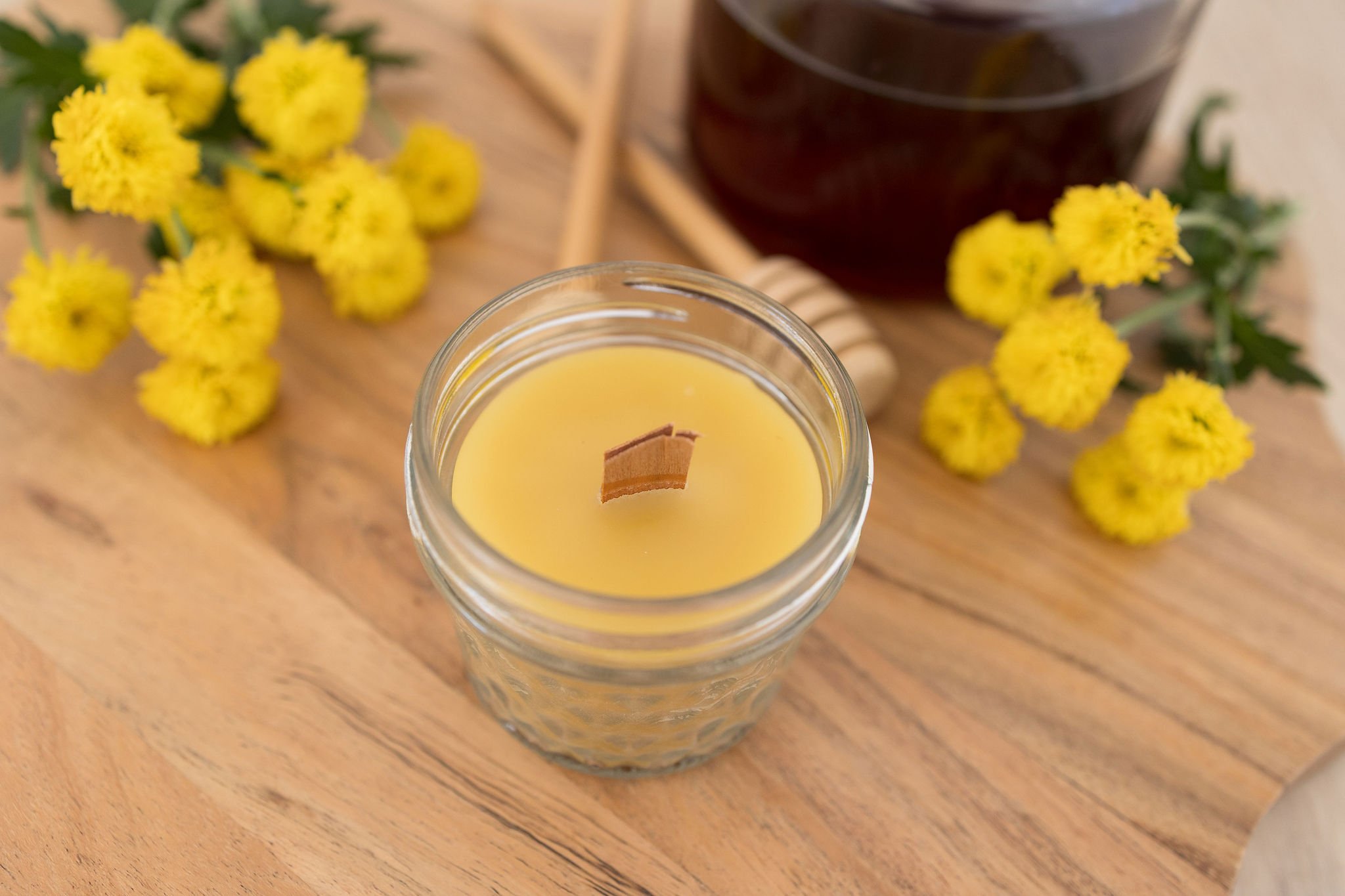 Handmade beeswax candle in glass jar with wooden wick, natural eco-luxury gift
