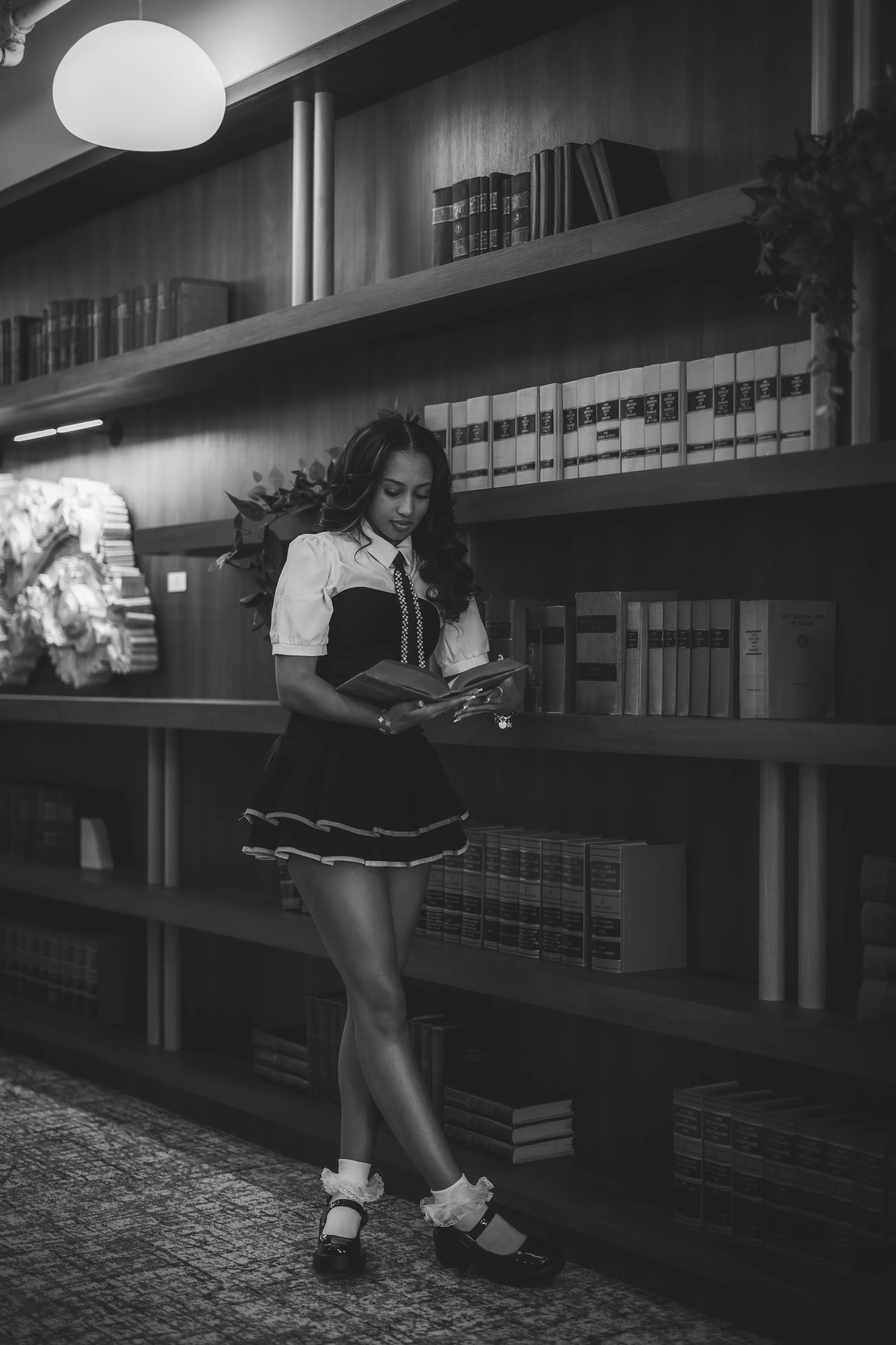 A woman in a vintage maid costume reading a book in a library.
