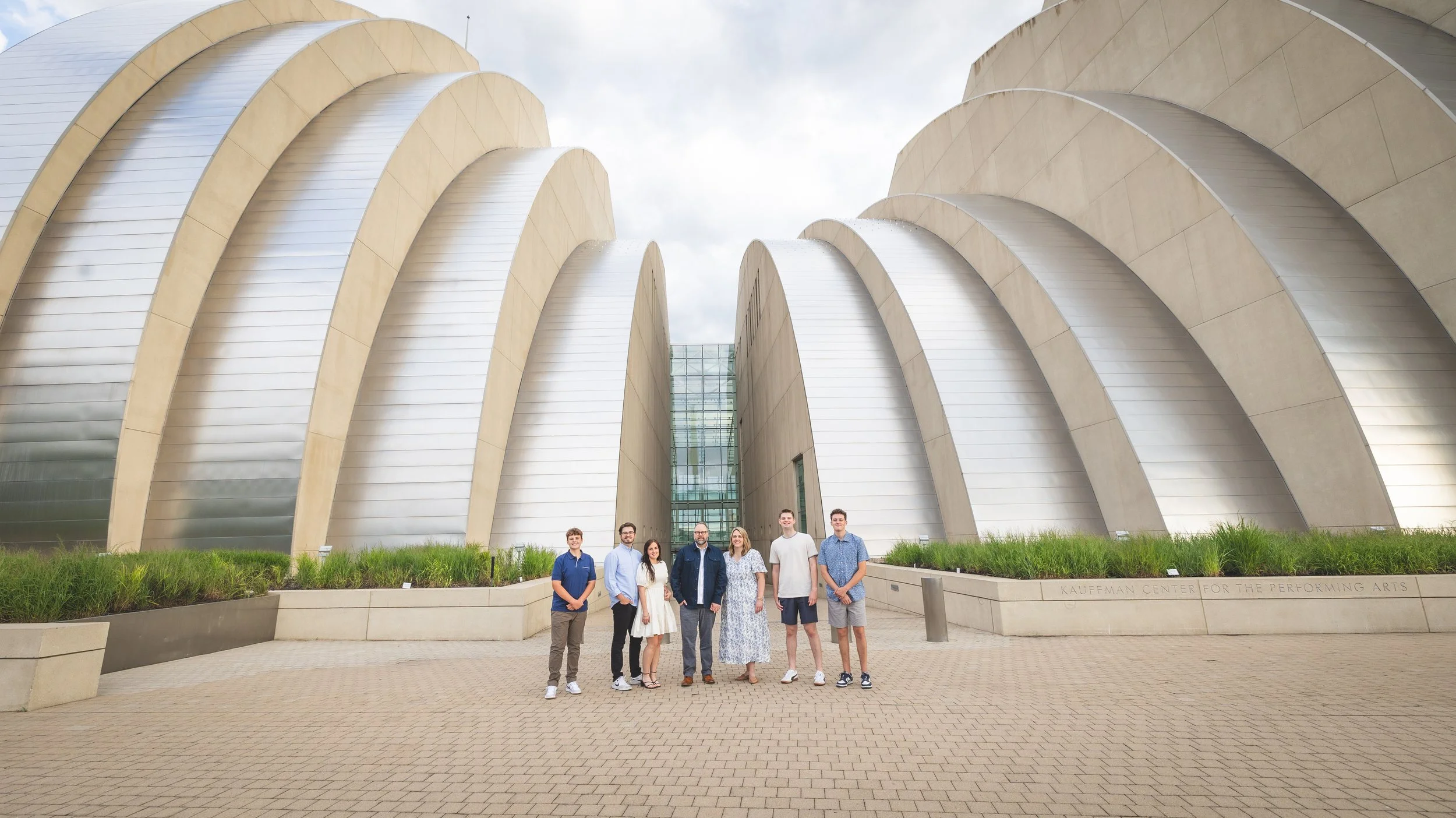 A group of seven people standing in front of the Walt Disney Concert Hall with its distinctive metallic, curved architecture.