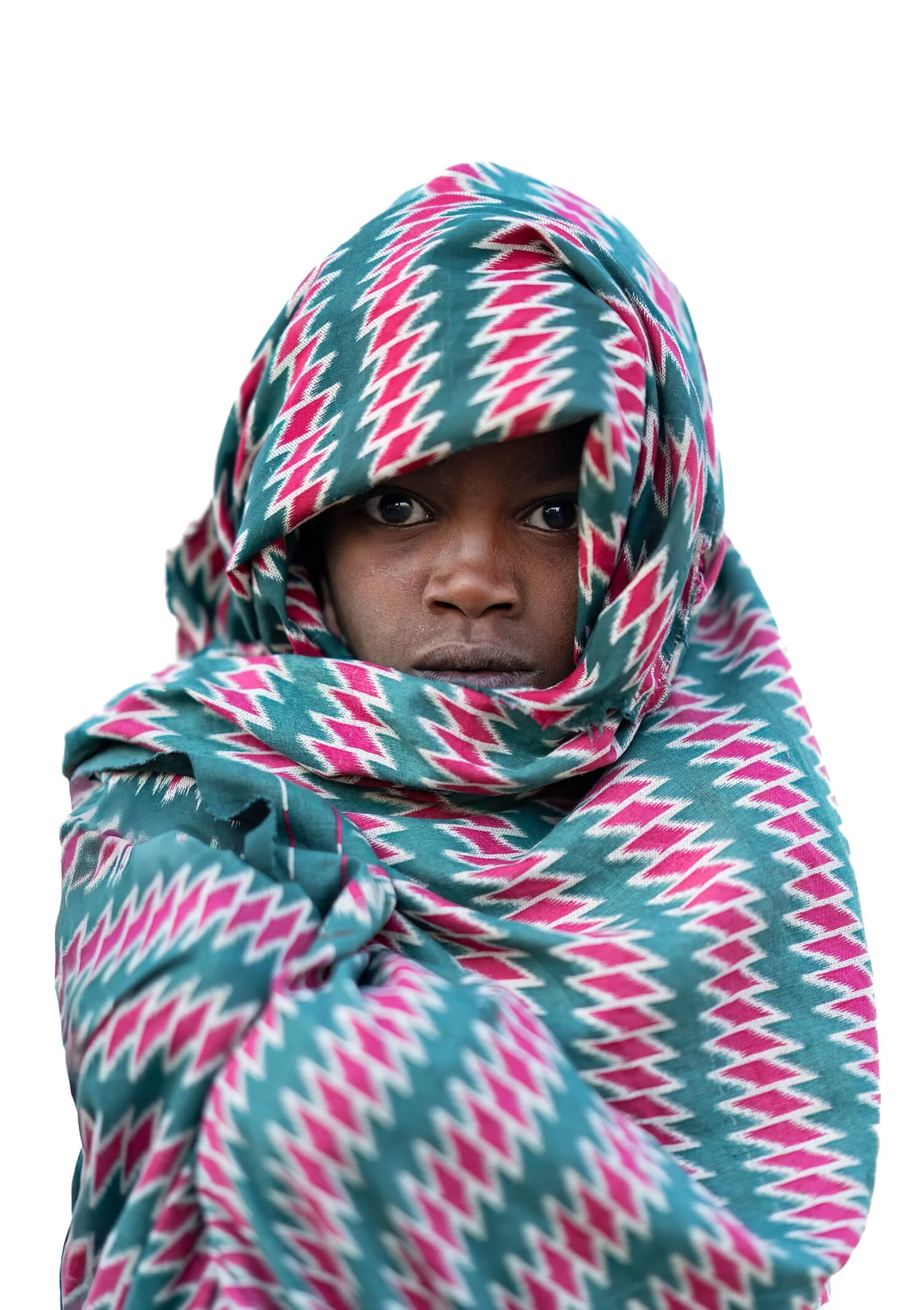 A young boy outside a Lalibela church. He is wearing a typical colorful patterned shawl. Photographed in Lalibela, Ethiopia.