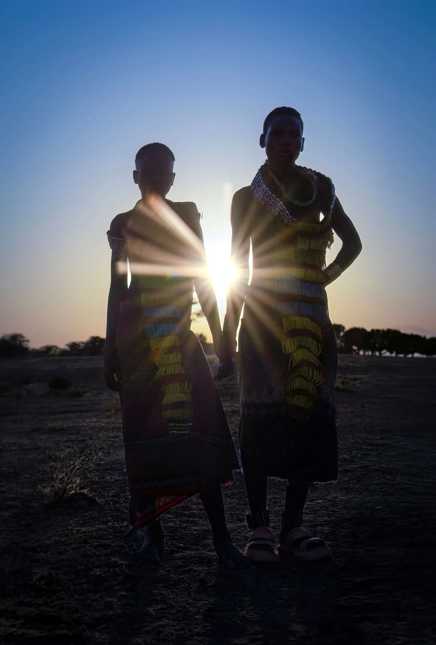 Two sisters in the Omo Valley, Ethiopia holding hands at sunset.   