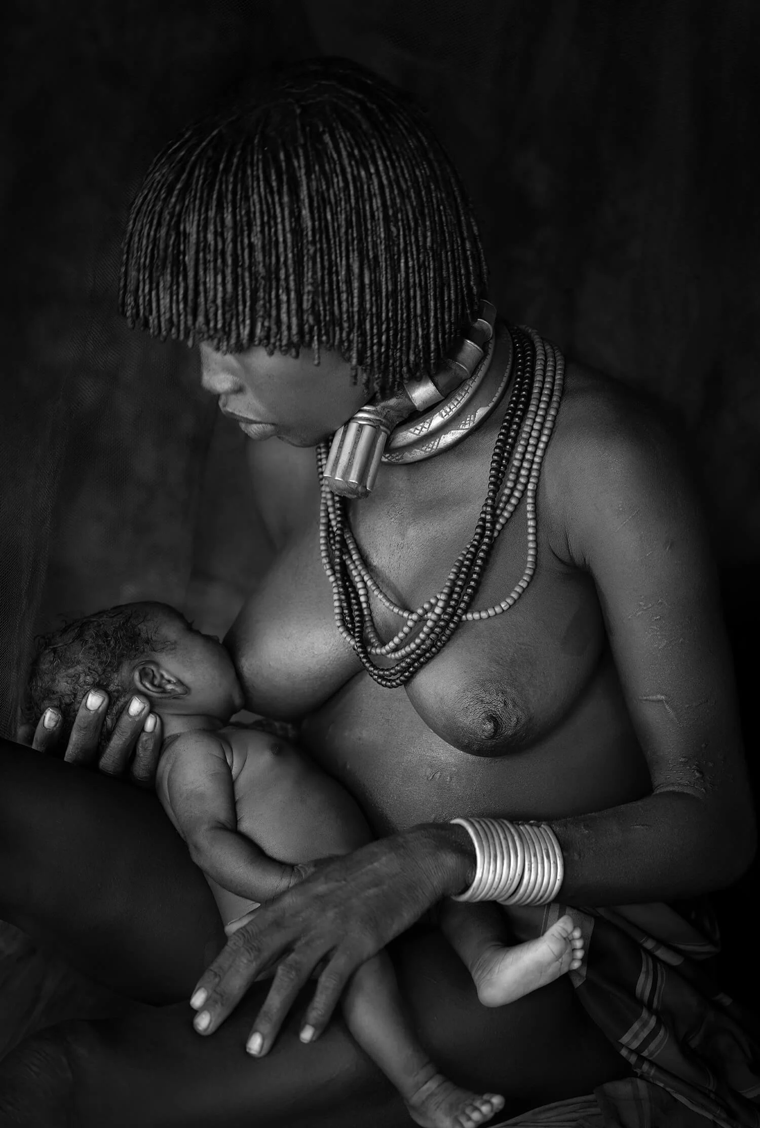 A mother from the Hamar tribe sharing a moment of love and nourishment with her little one.  Photographed in the Omo Valley, Ethiopia.