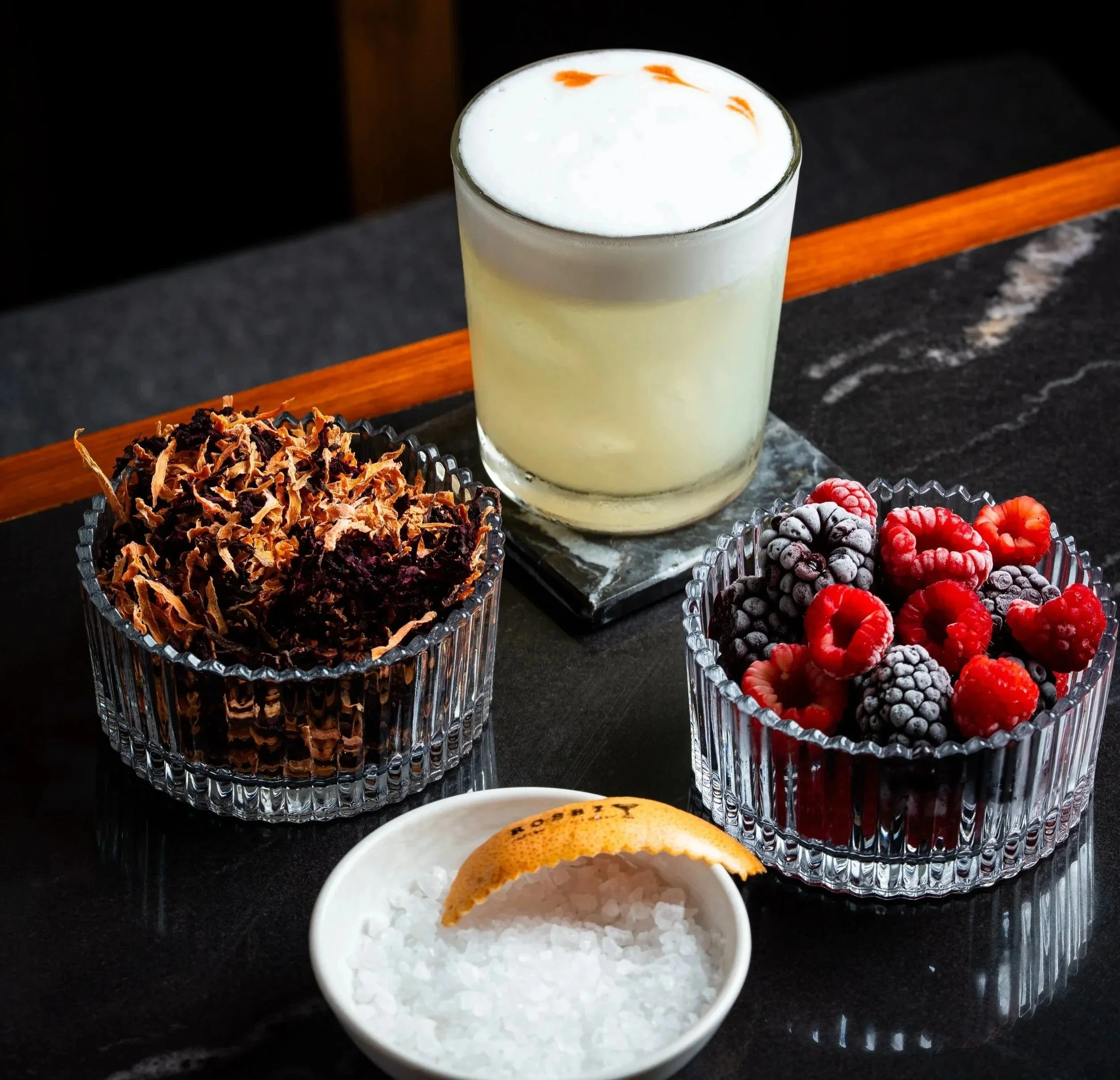 Vasos con hielo, frutas congeladas, una bebida cremosa y sal en un platito.