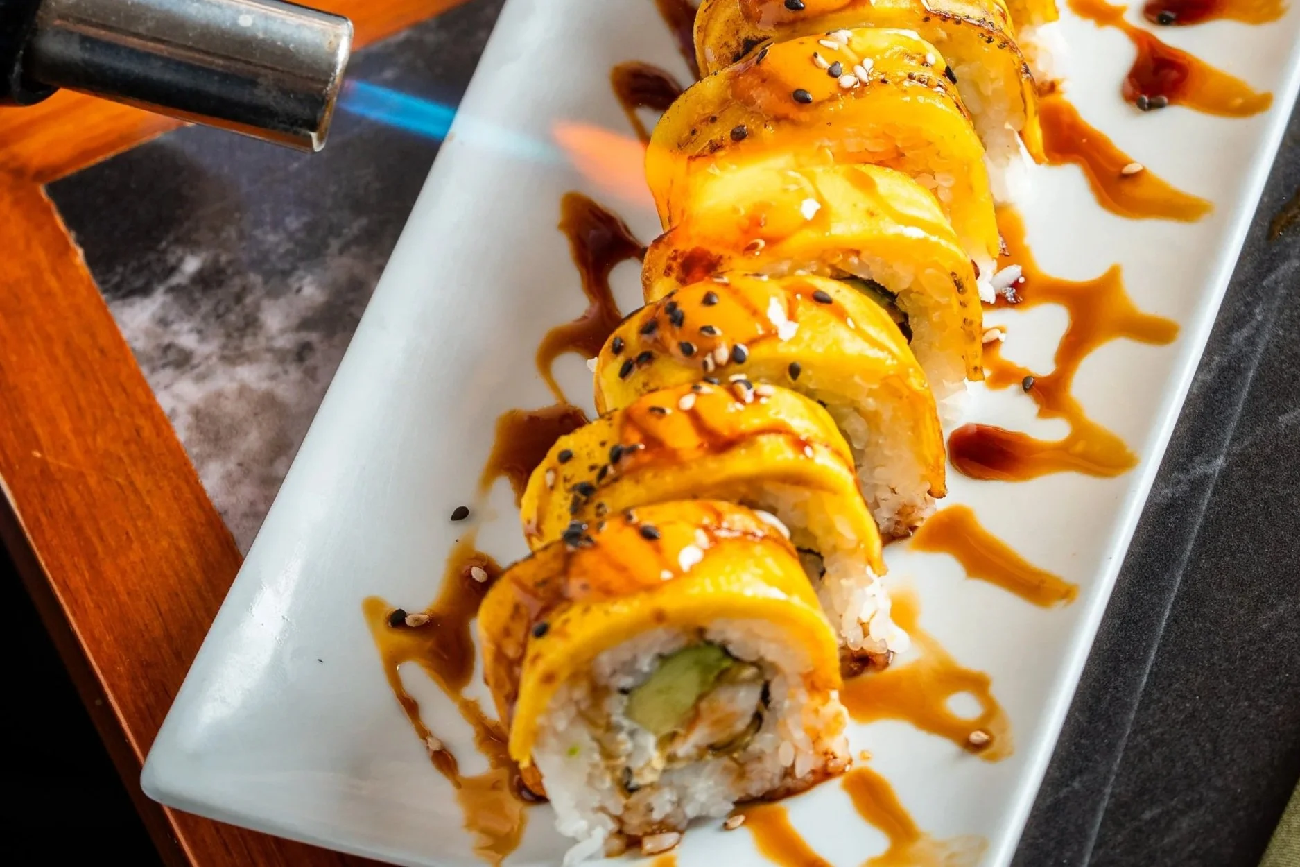 Rollos de sushi decorados con salsa de marihuana, semillas de sésamo y sirviéndose en un plato blanco.