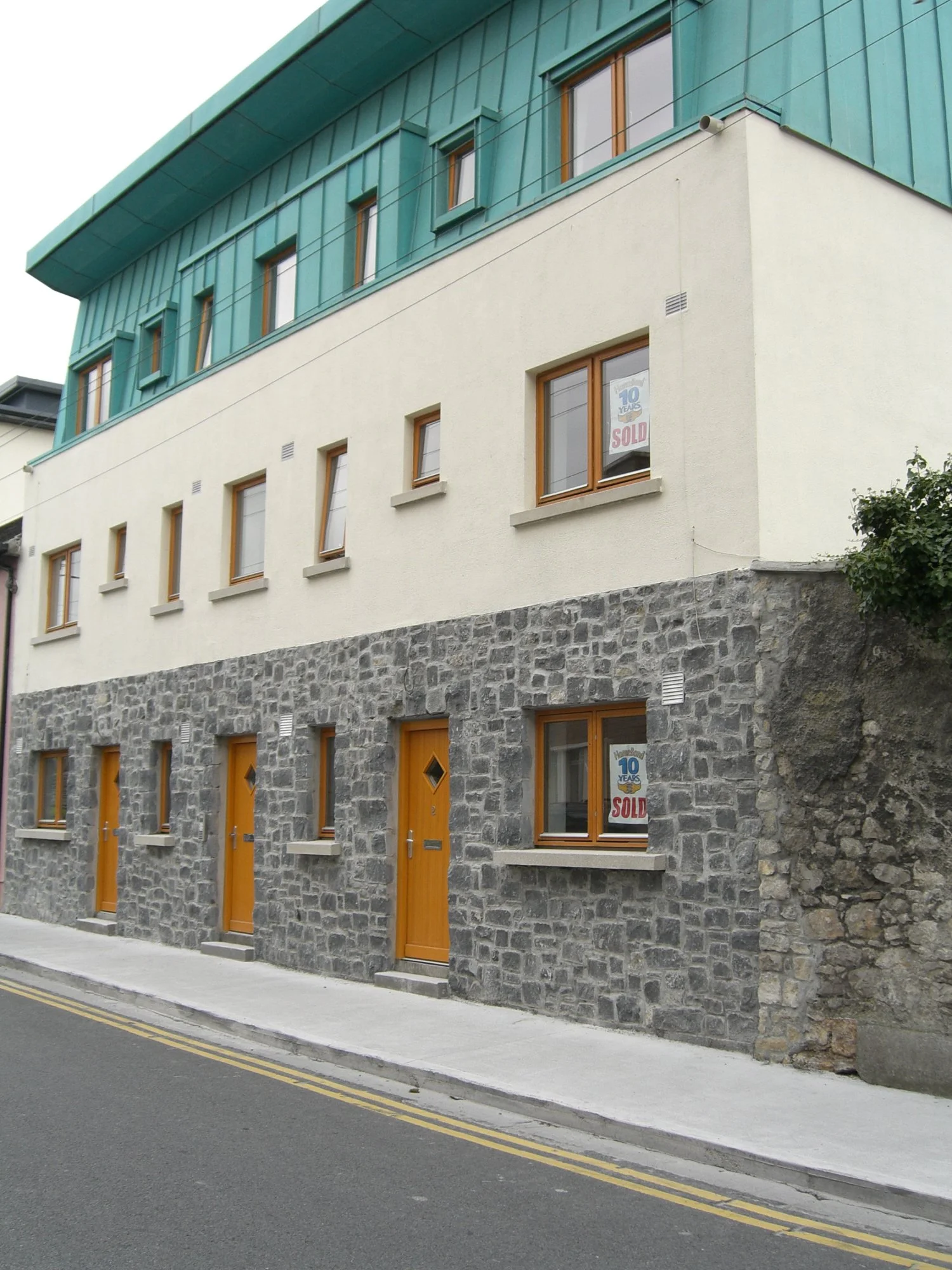 Two-story building with stone facade and teal roof