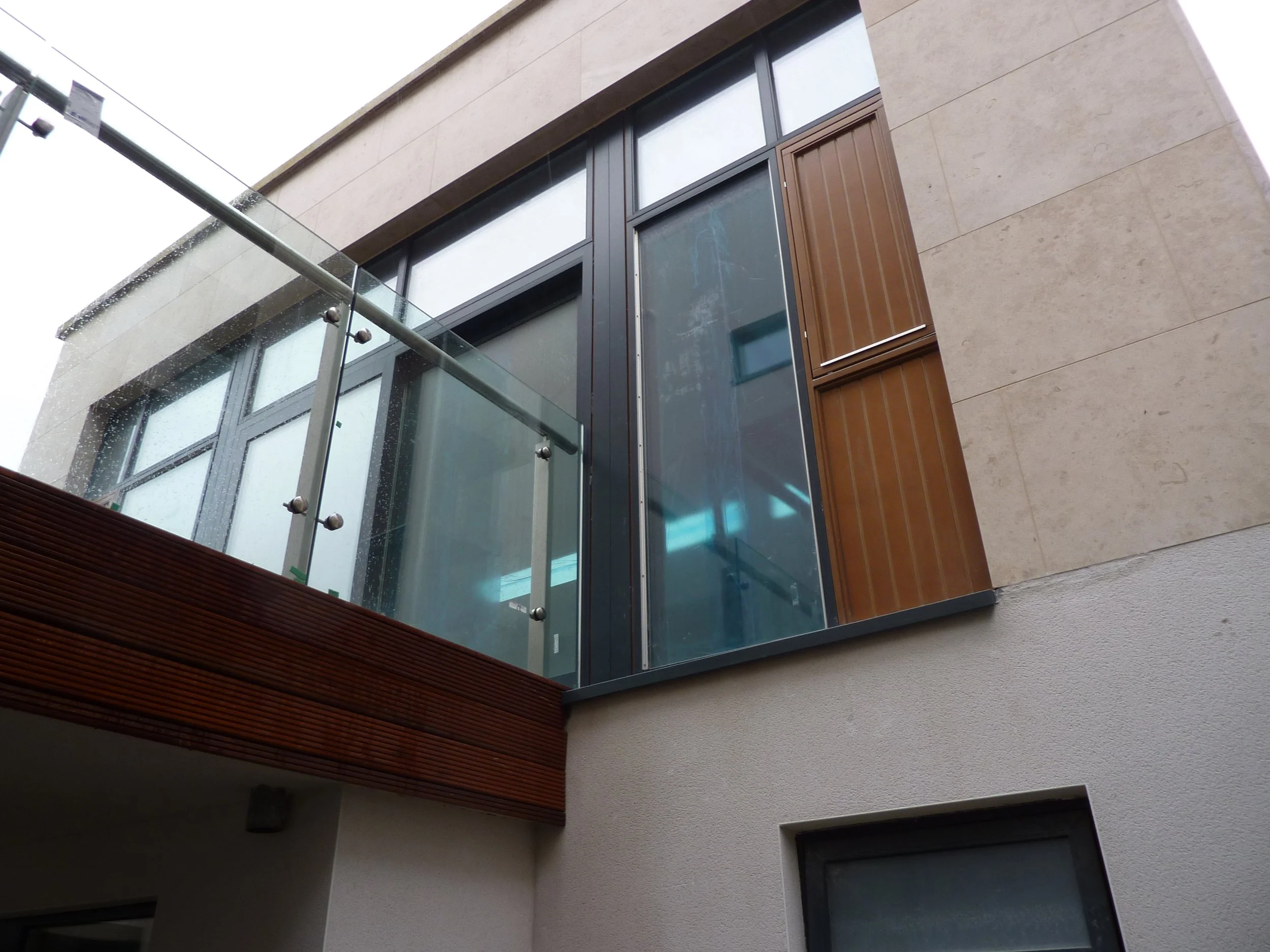 Modern building facade with large windows and glass railing on a balcony.