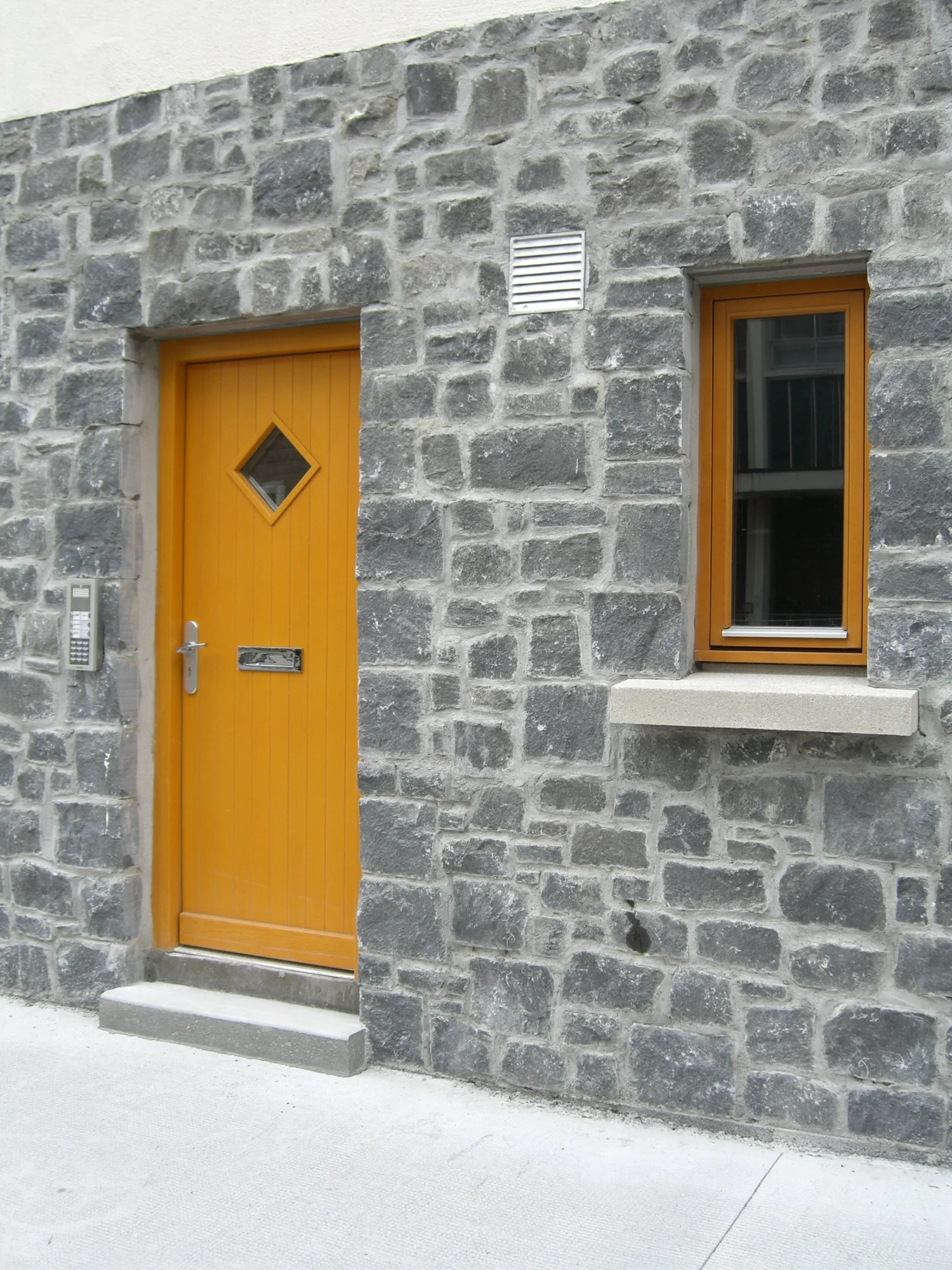 Stone facade with an orange door and window