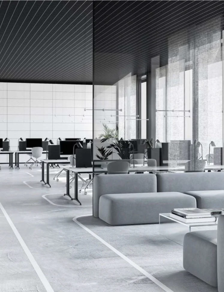 Modern office space with rows of desks, chairs, and a waiting area with sofas and a coffee table. Bright, with large windows and minimal decor.