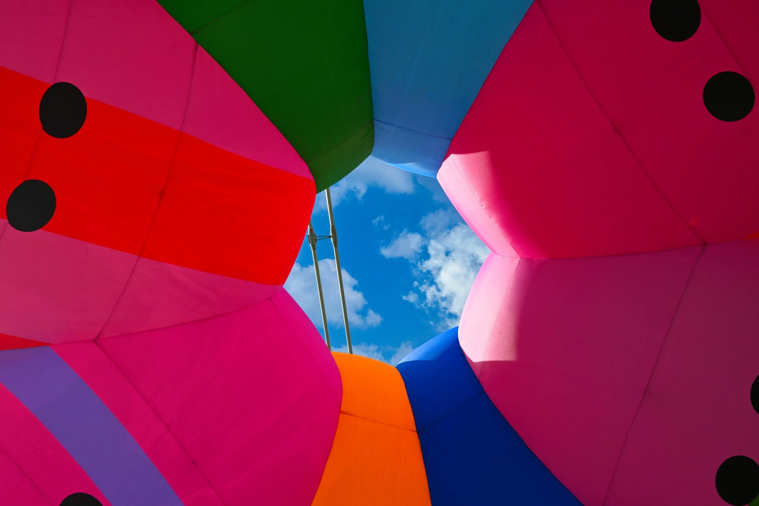 Colorful hot air balloon viewed from underneath against a blue sky with clouds.