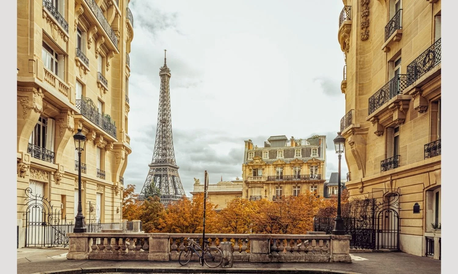 View of the Eiffel Tower framed by classic Parisian buildings, showcasing warm neutral tones — part of Élan Petite's spring capsule style guide.