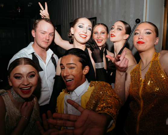Group of performers in a dynamic stage show with bright lighting and costumes.