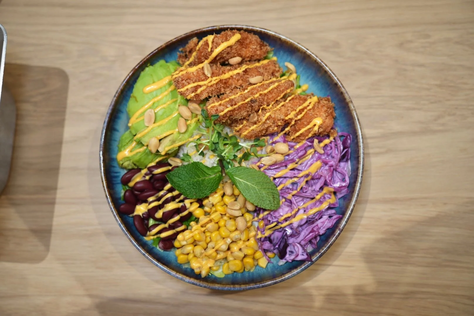 Buddha-Bowl mit Bauernfrikadellen, Salat, rote Kidneybohnen, Mais, Rotkraut, frischen Kräutern, mit Tahini-Dressing