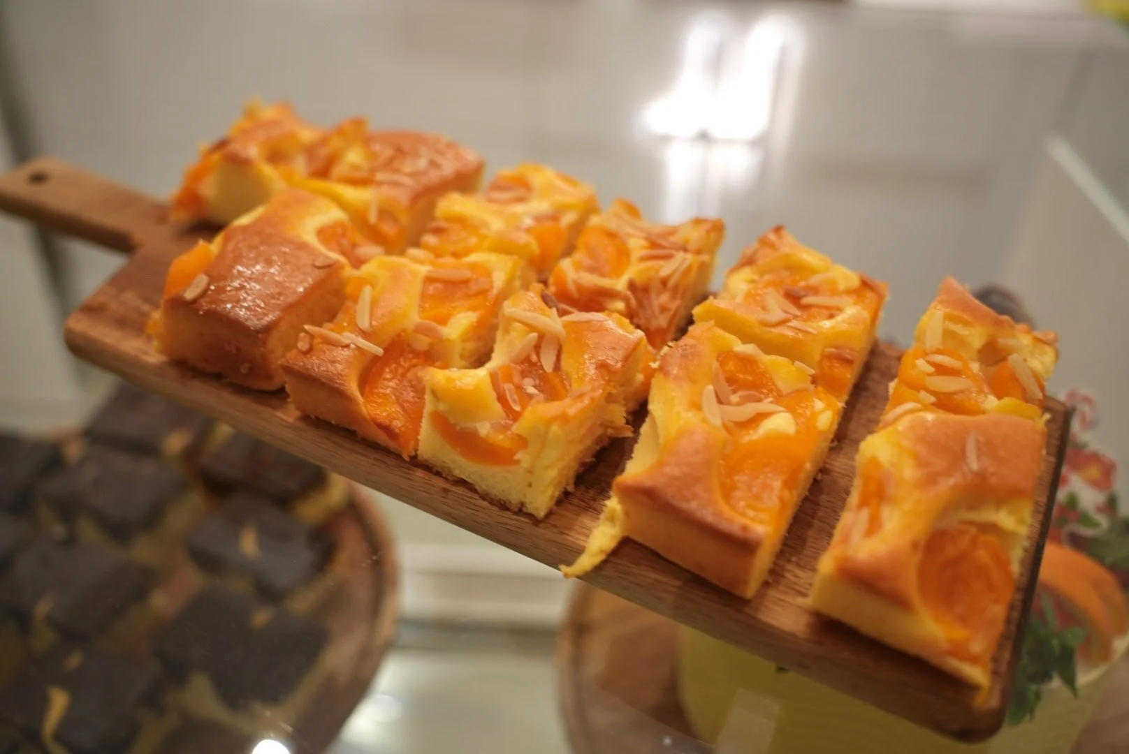 Kuchen mit Aprikosen und Mandelblättchen auf einem Holzbrett.