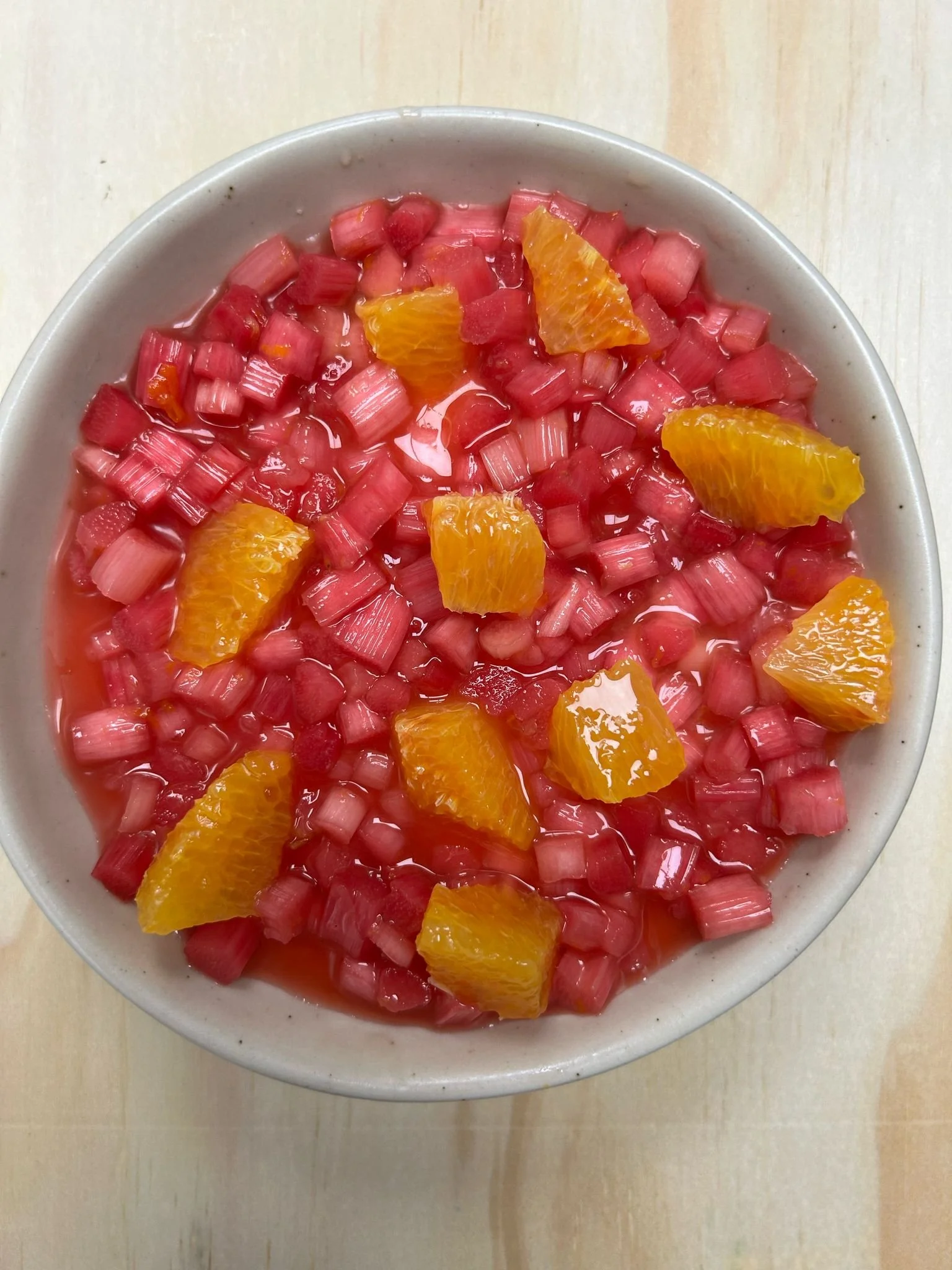 Bowl of diced rhubarb and orange pieces in syrup
