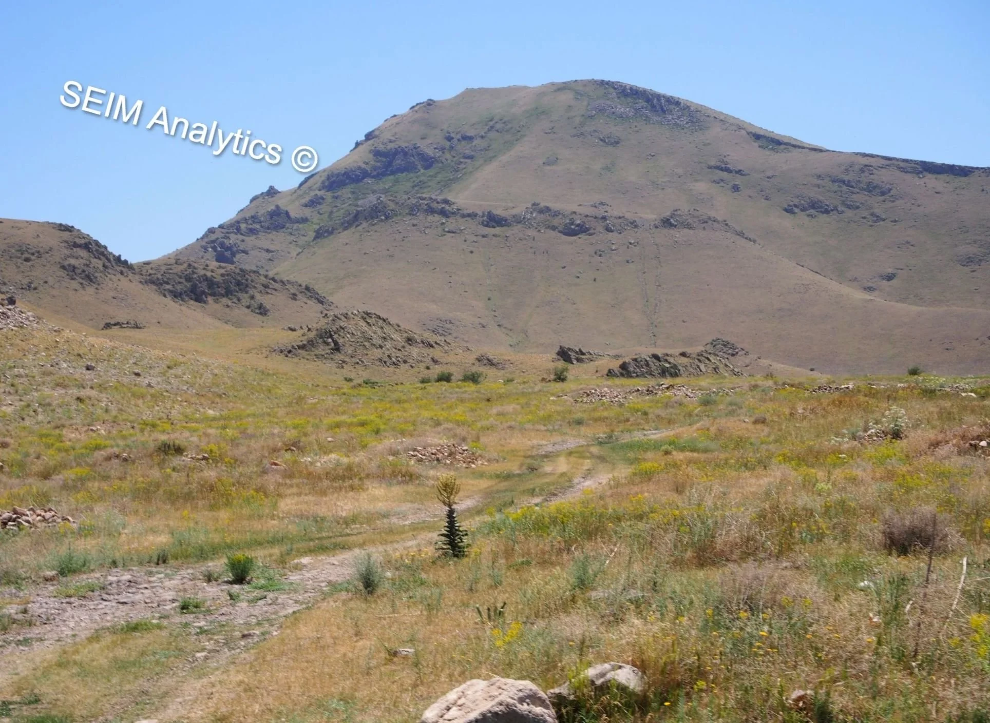 Open grassland with a dirt trail leading towards a mountain in the western part of Armenia, Talin area of Aragatsotn Province.